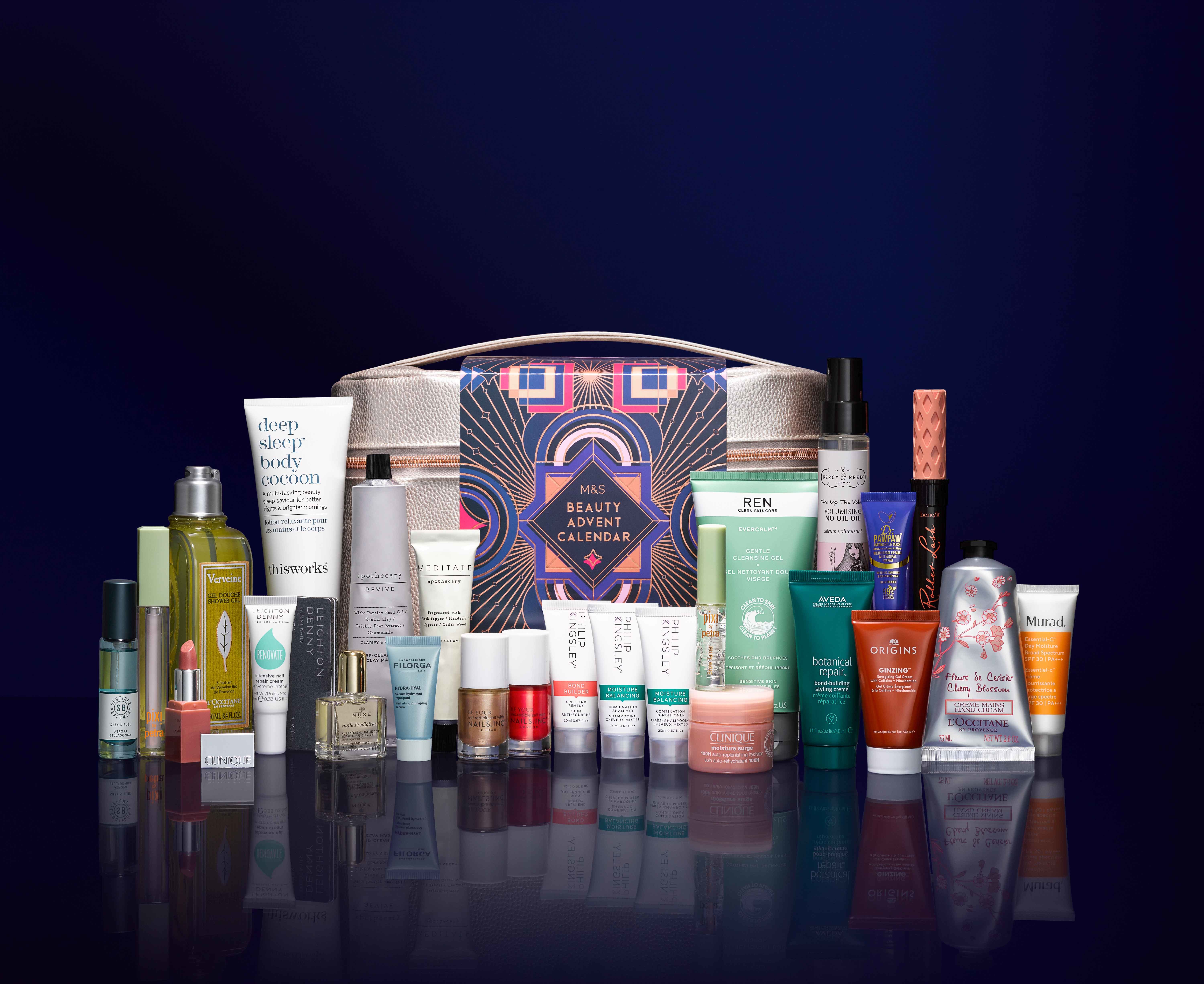 An assortment of beauty products arranged in front of a Marks and Spencer beauty advent calendar box on a dark background and reflective surface.