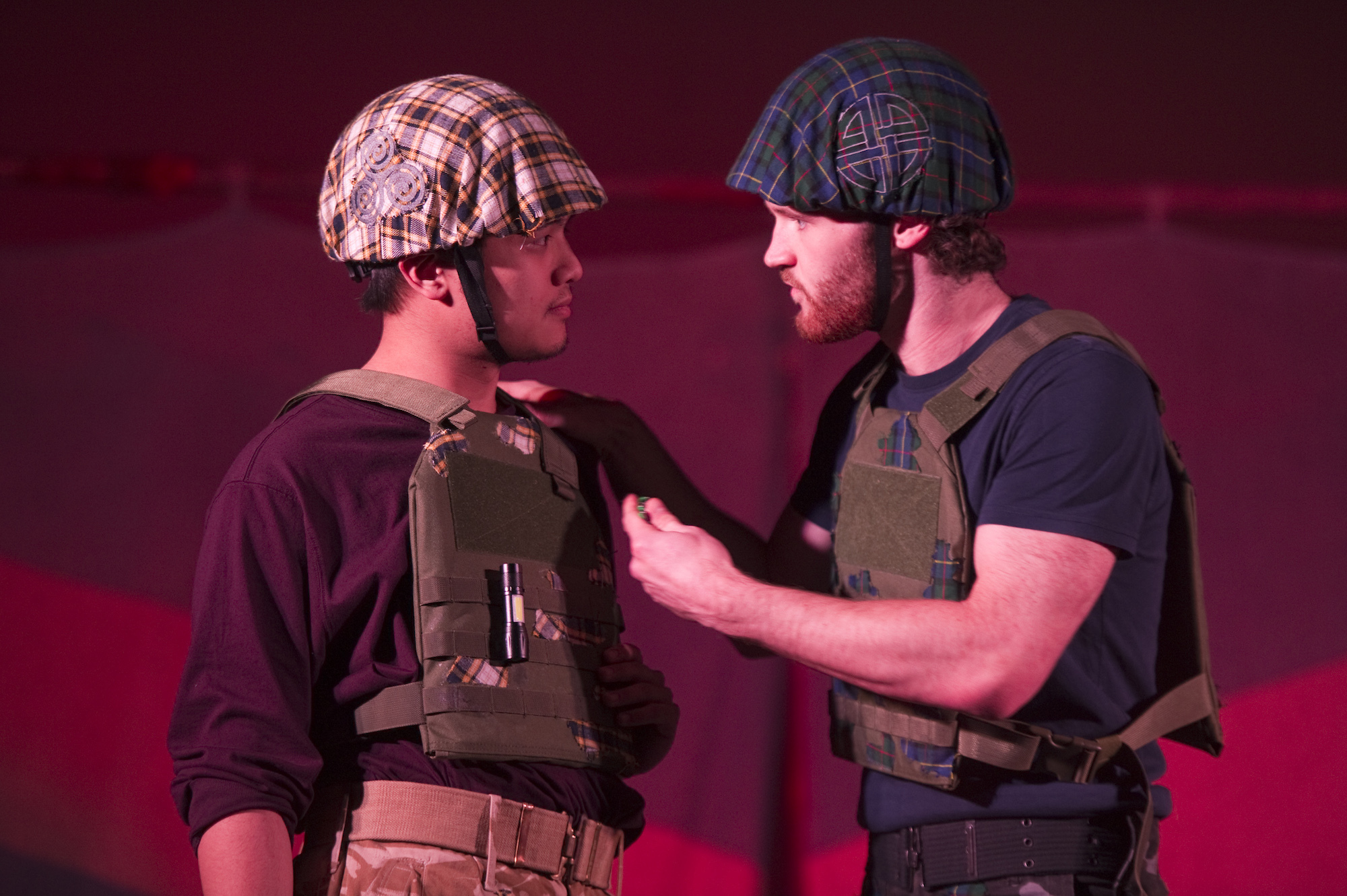 Two BA (Hons) Acting students on stage performing Macbeth. Both performers are wearing military fatigues and looking at each other seriously.