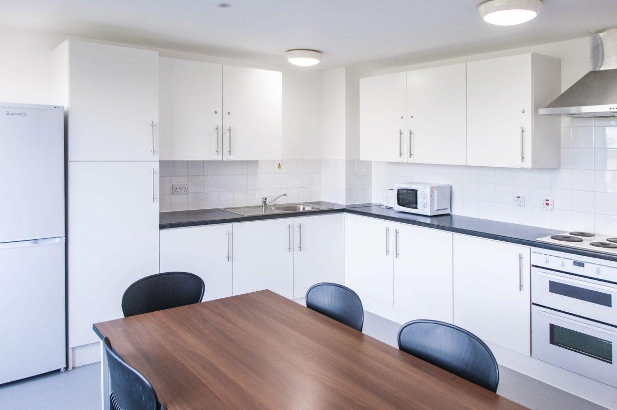 Kitchen featuring a wood table and back chairs, a black countertop and white cupboard