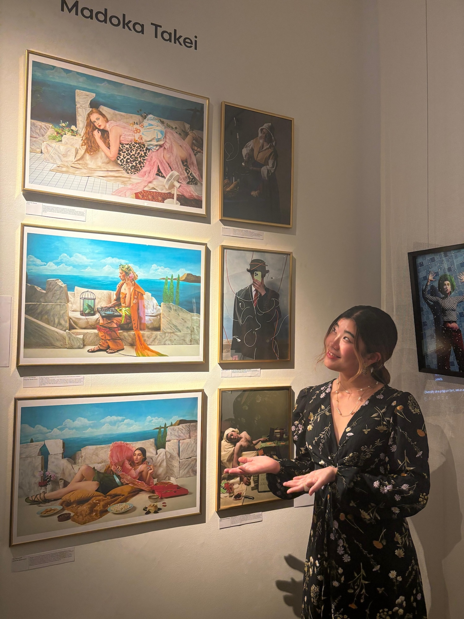 M Takei standing beside wall displaying six framed paintings under "Madoka Takei" text in gallery setting.