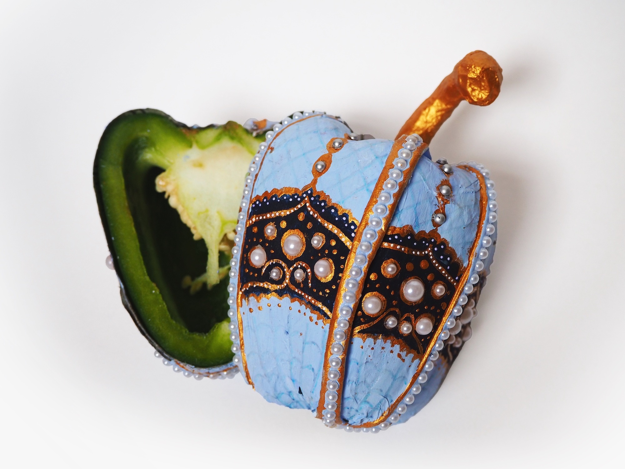 A bedazzled green pepper with pearls, golden accents, blue and light blue shades.