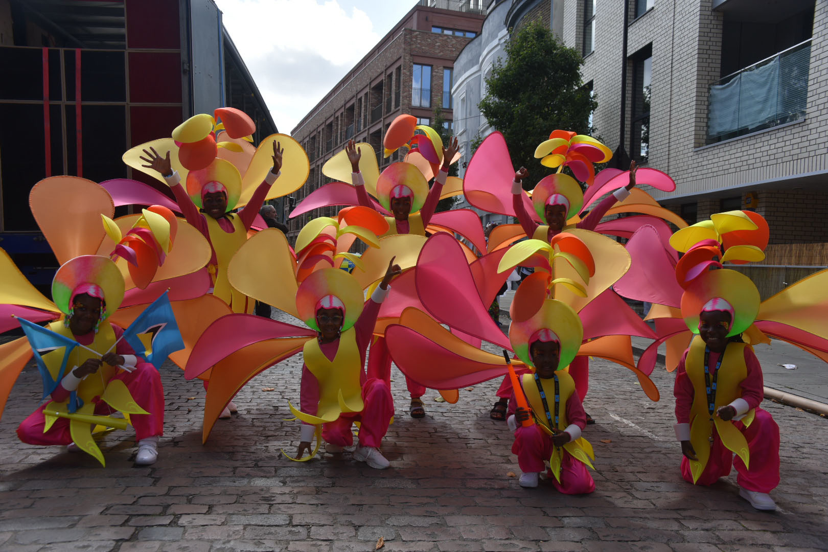 A group of performers posing on a street wearing bright, multicoloured costumes.