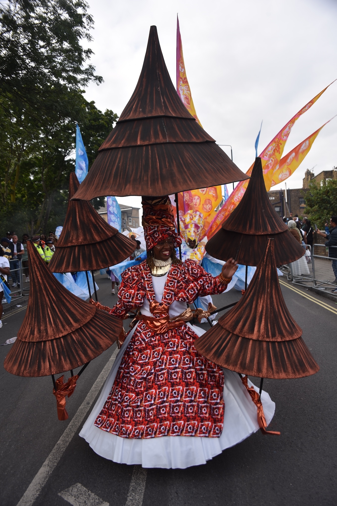 A carnival performer wearing a white and red costume with five cone attachments.