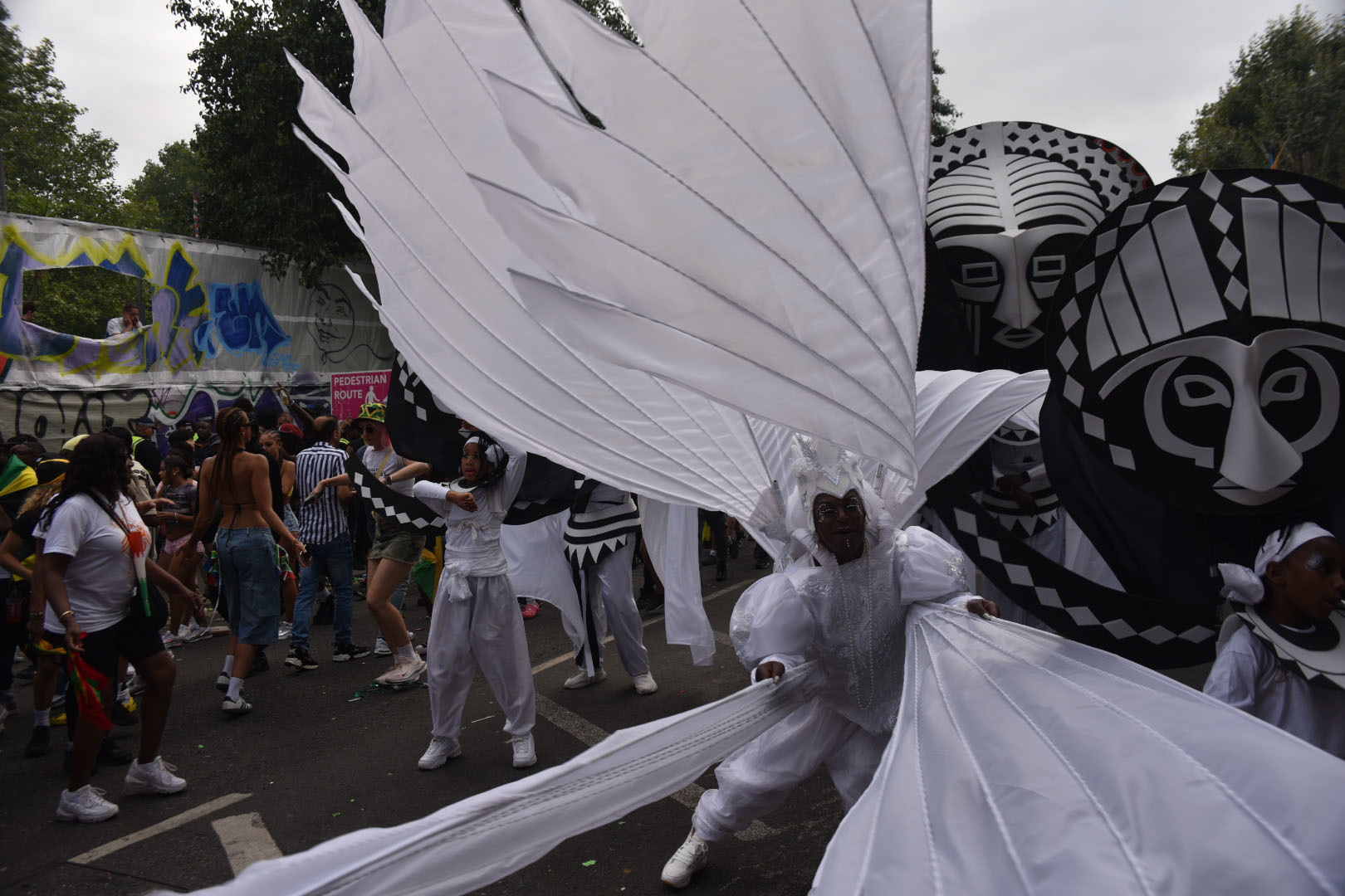 A carnival performer dancing in a street wearing a large white costume.