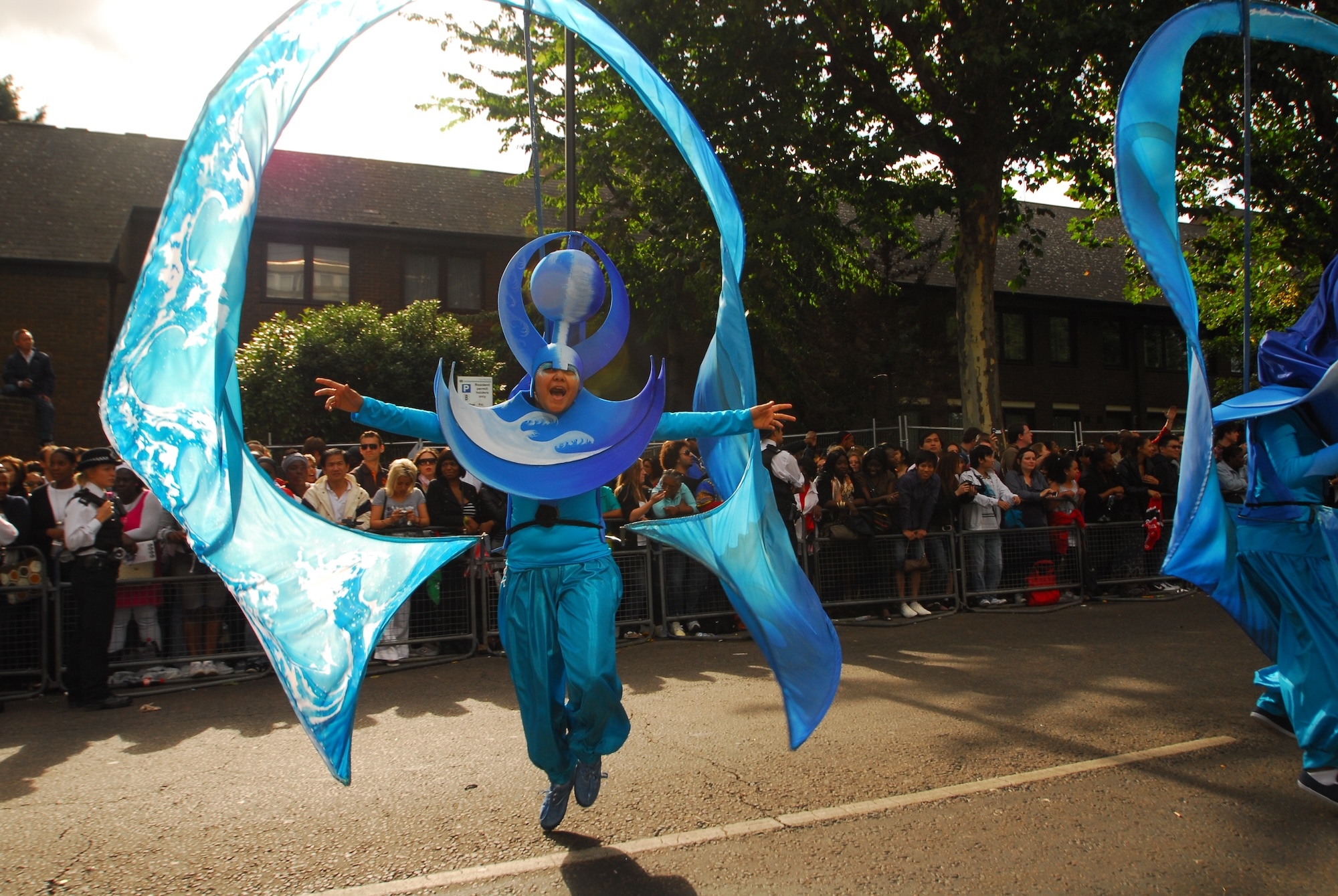 A carnival performer swearing a blue costume and ocean-themed headdress.