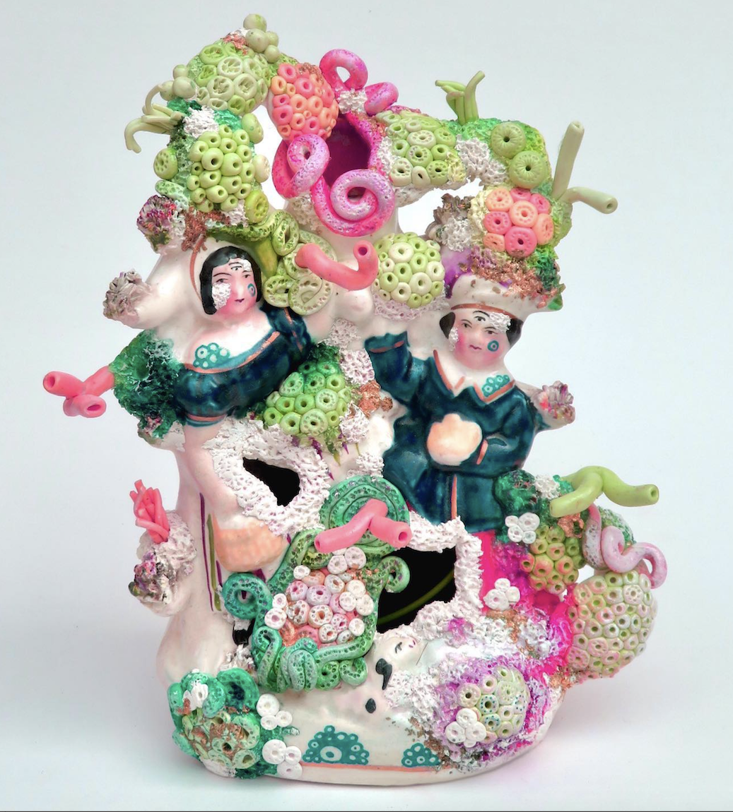 Detailed, colourful coral ornament with two people, bright green and pink, white background.