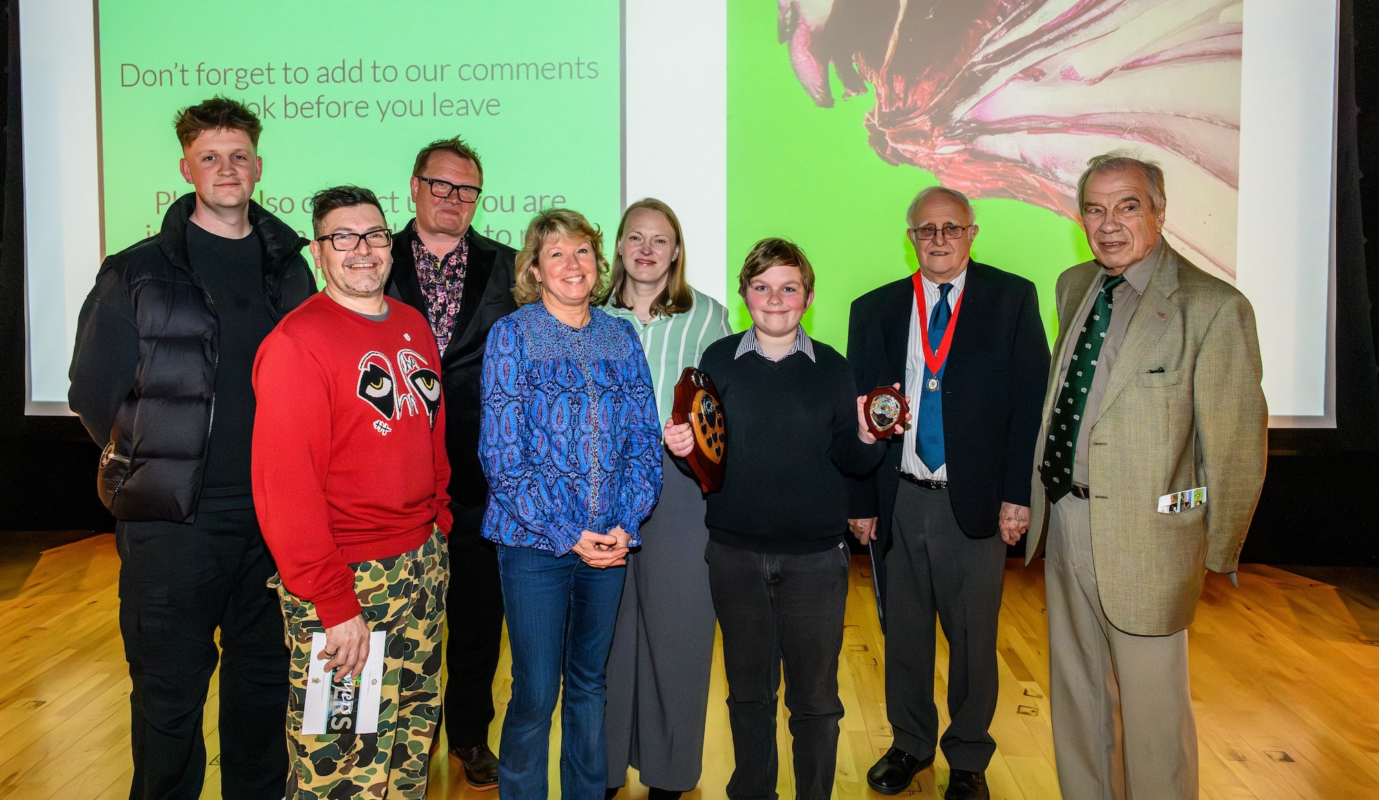 A group of photography competition winners and judges pose for a photo