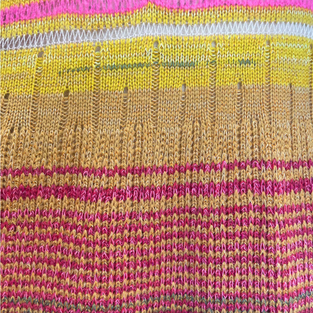 Knitted fabric with horizontal stripes in pink, yellow, white, and brown. Various stitch patterns including stockinette and textured stitches.