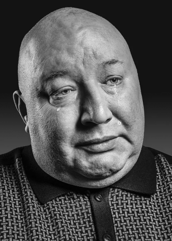 Black and white portrait of a man with tears rolling down his face.