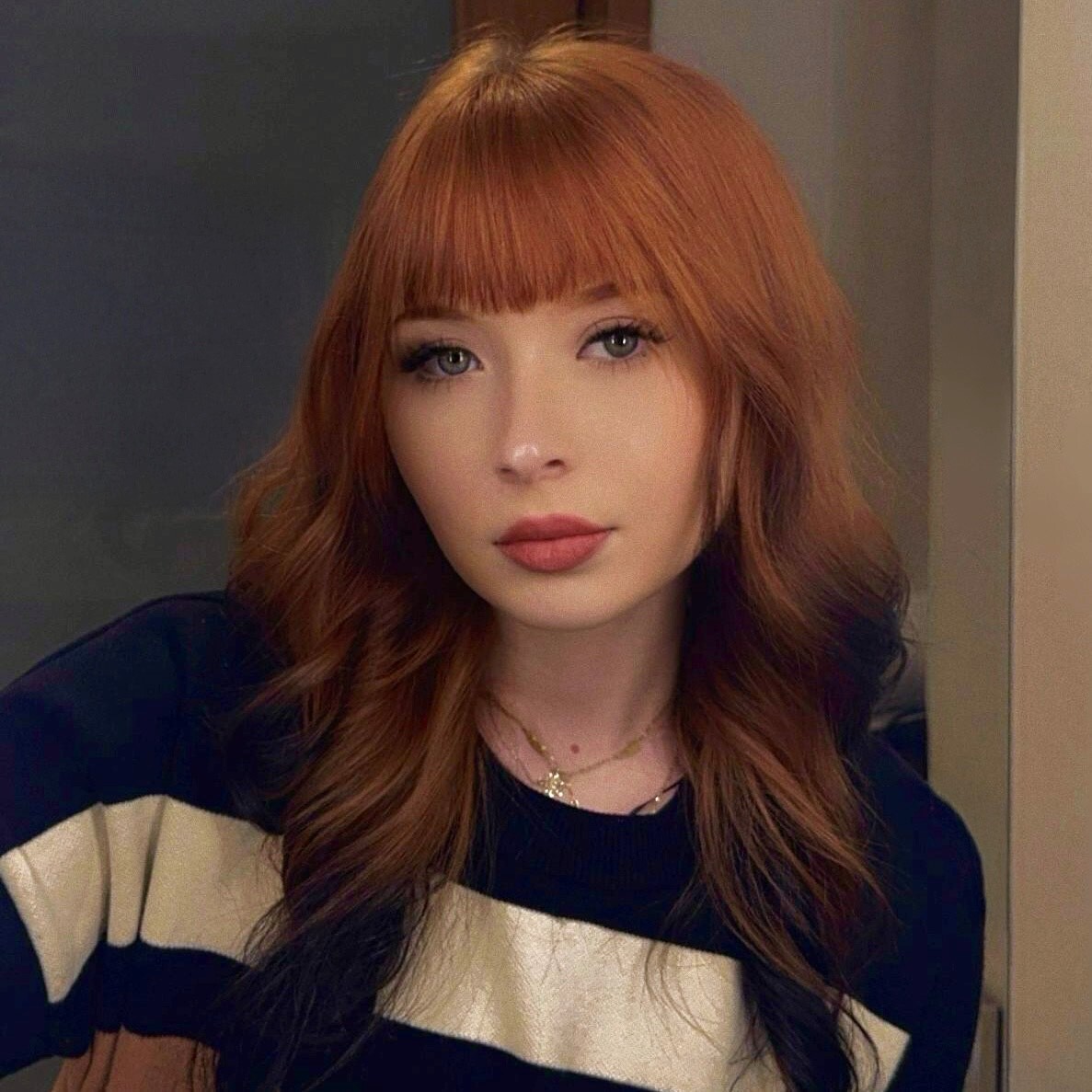 Headshot of Martyna Berk. She has ginger hair wearing red lipstick, a necklace and a black and white striped top.