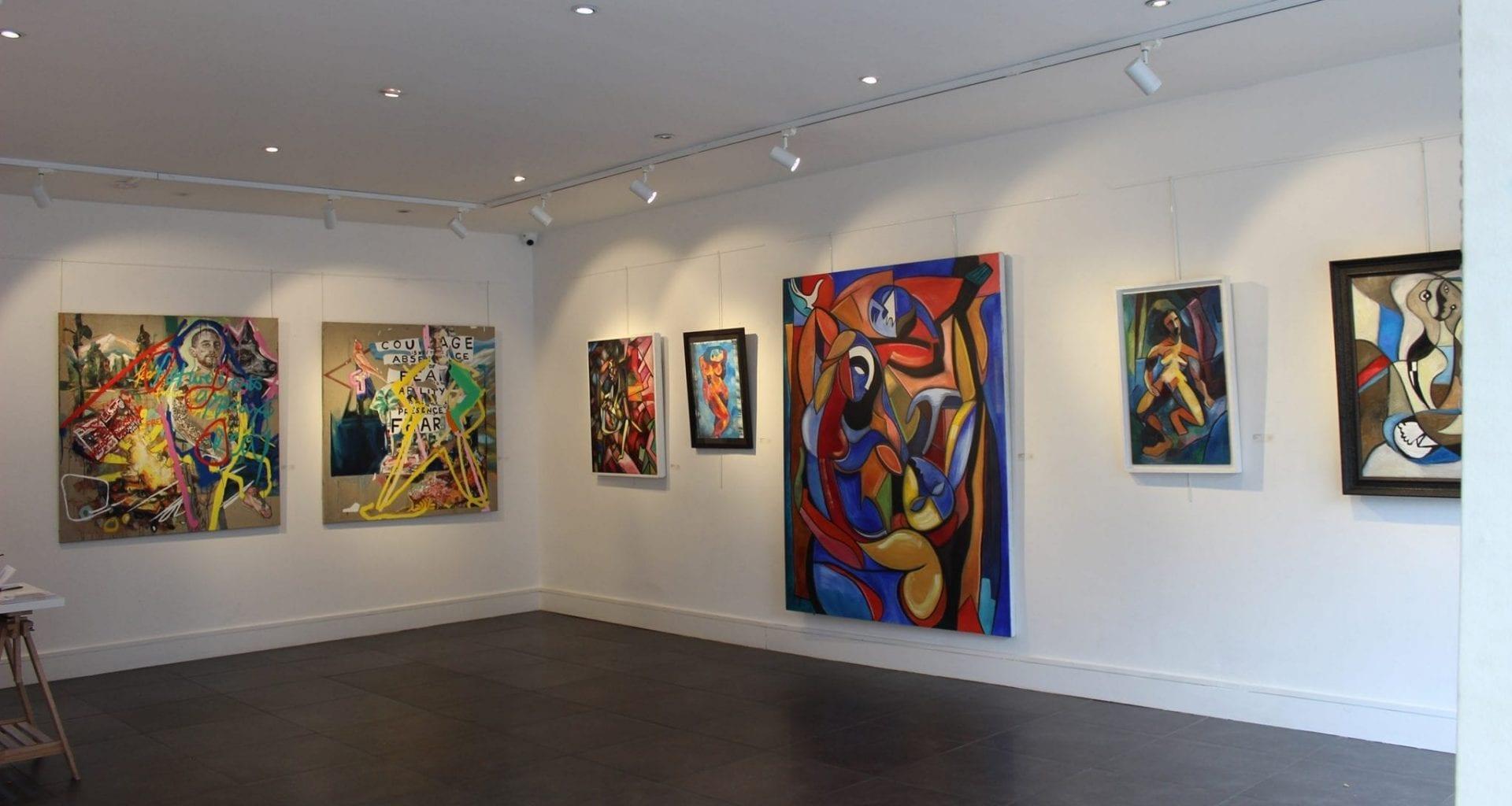 Corner of a gallery space with seven different artworks on display.