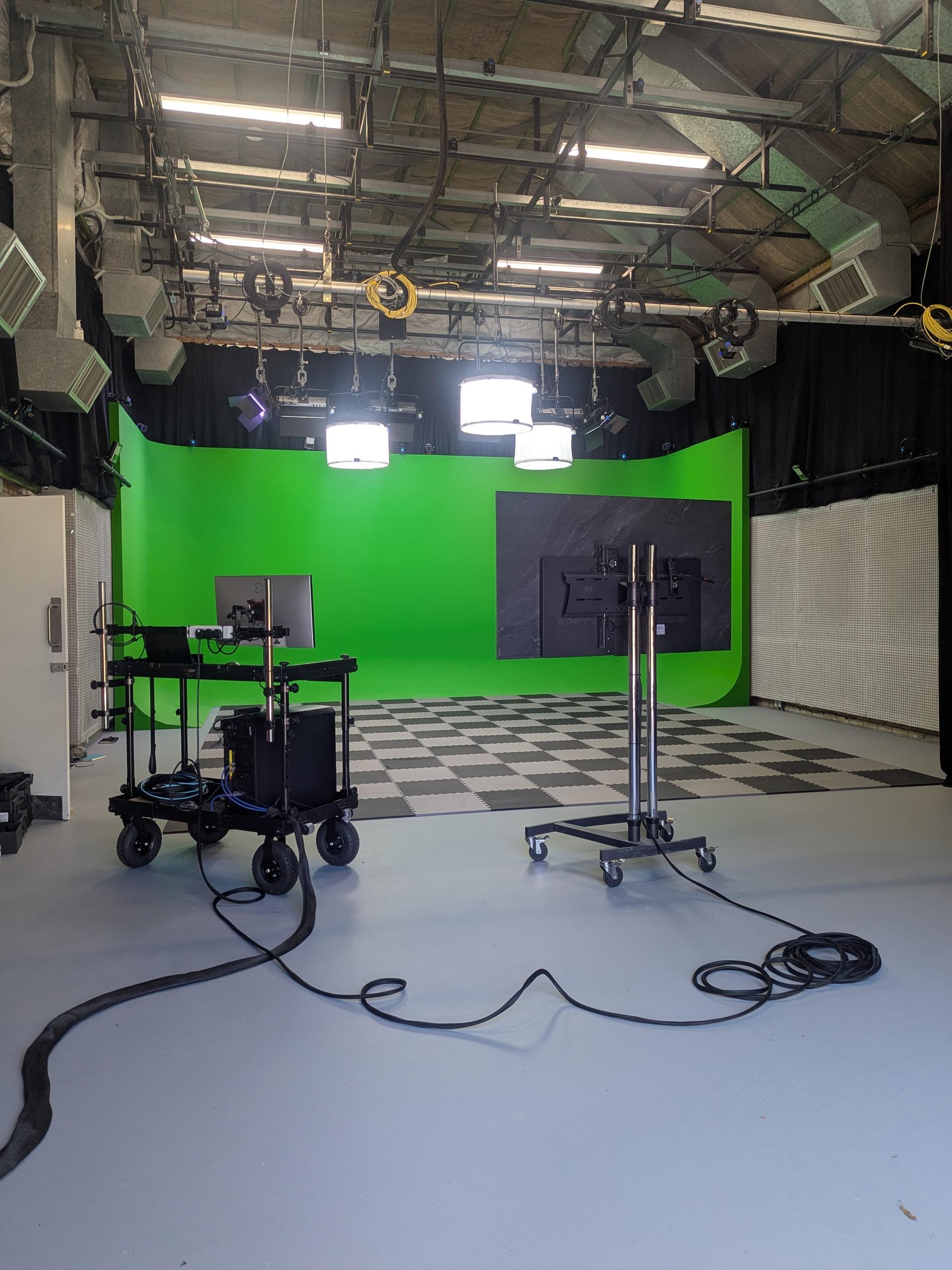 A film studio at Arts University Bournemouth with a trolley and a monitor facing away from the camera, and a Chroma-Key green screen surround backdrop set up for motion capture in the background.
