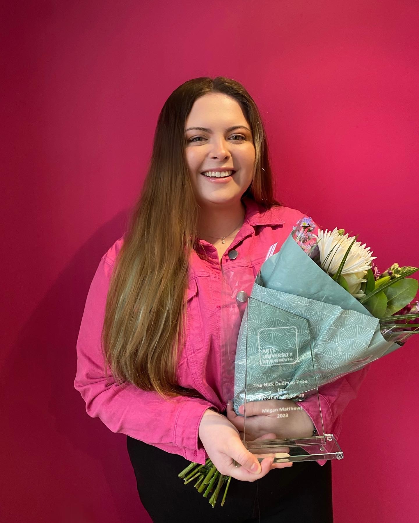 Portrait for M Matthews holding a bouquet and a glass trophy.