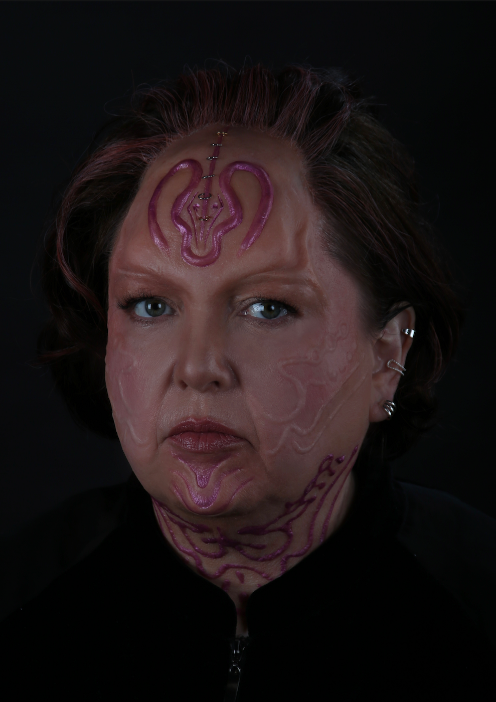 Headshot of a model with pink tattoos on their face and neck.