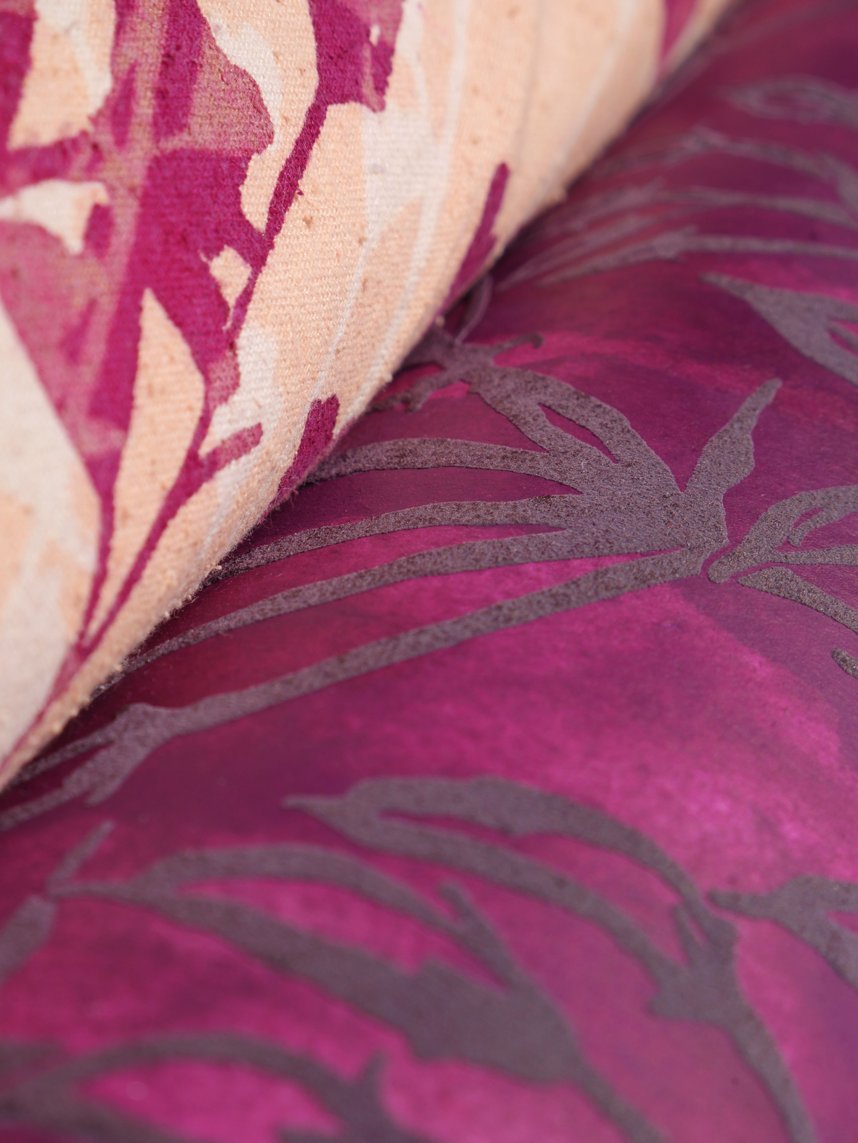 A close-up image of two fabric swatches overlapping. The top swatch features a light cream background with pink floral patterns, while the bottom swatch has a deep magenta hue with grey leaf outlines.