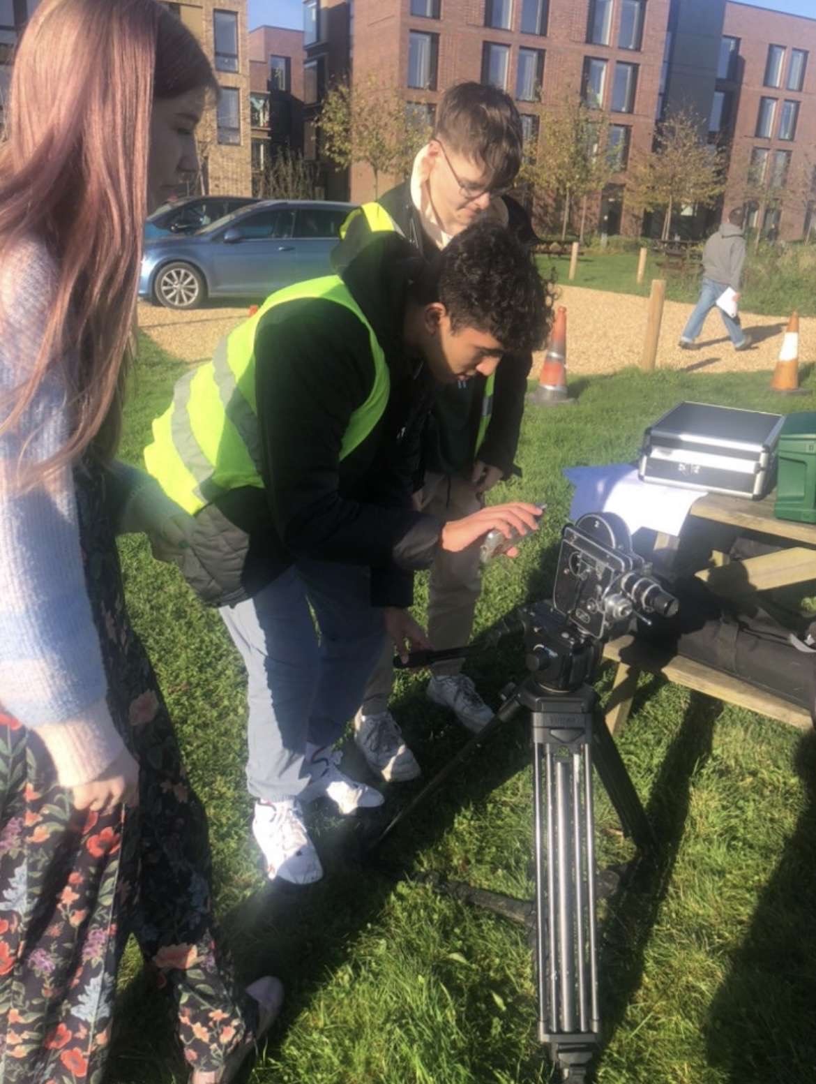 Three BA (Hons) Film Production students working with a Bolex camera outside Campus Halls at Arts University Bournemouth.