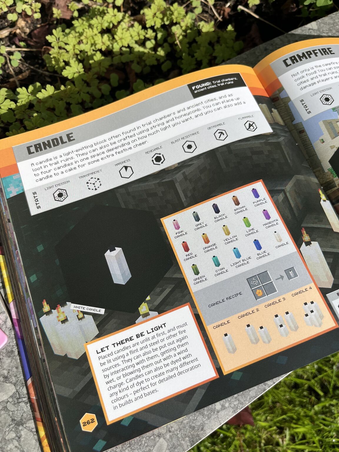Open instruction manual for candle-making kit showing orange-bordered pages with white candle, coloured wax chips chart, and text sections on dark background.