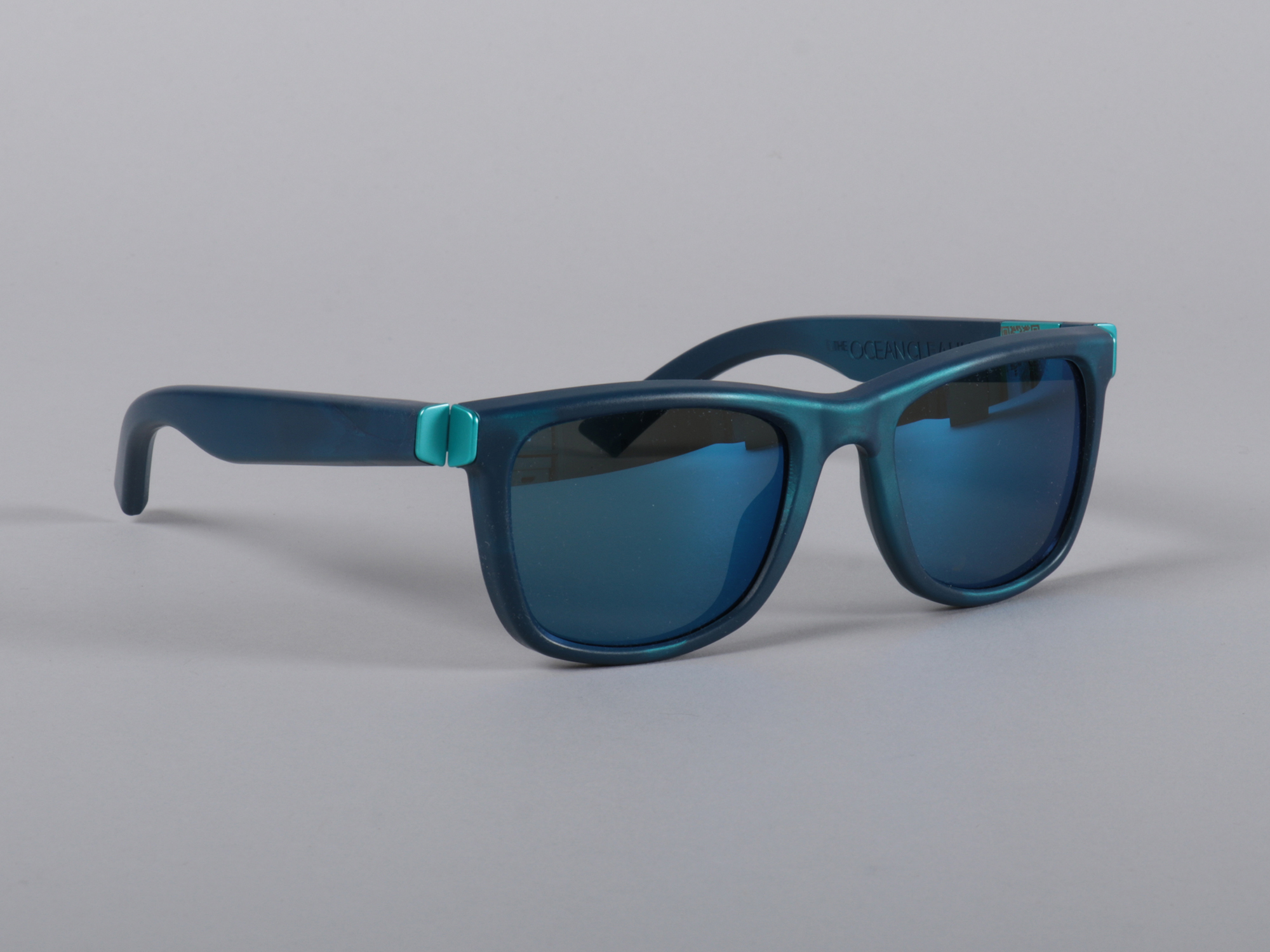 A pair of plastic sunglasses on a plain surface and background.