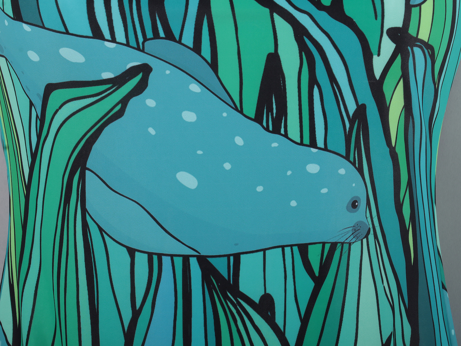 Close-up of a swimming costume pattern showing an illustration of a seal swimming through a seaweed forest.