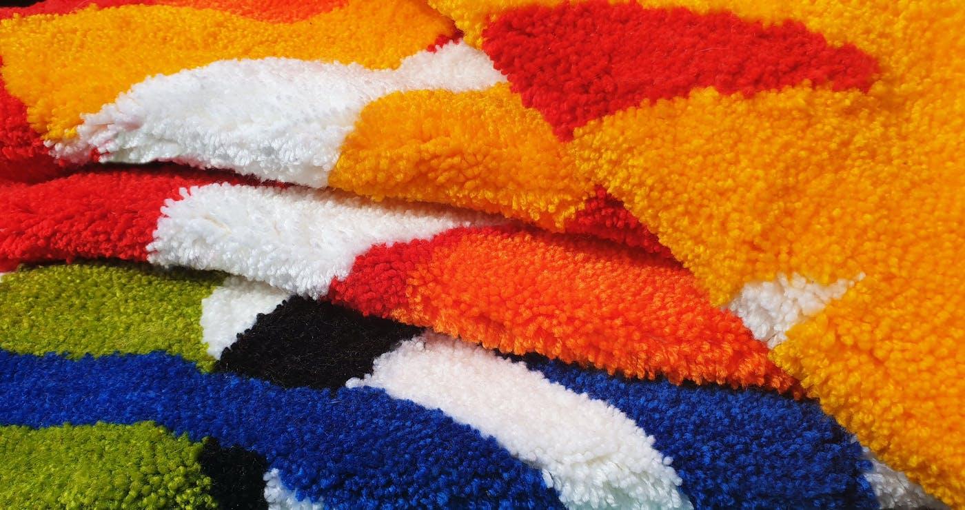 A pile of tufted rugs in different colours.