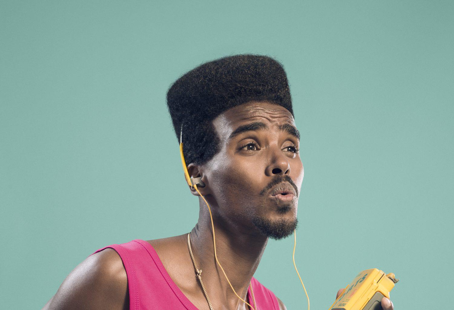 A man wearing headphones sings or whistles.