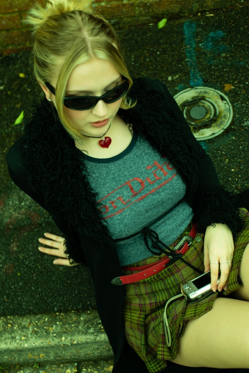 Model sat on the side of the curb wearing fashionable fit, green tint.