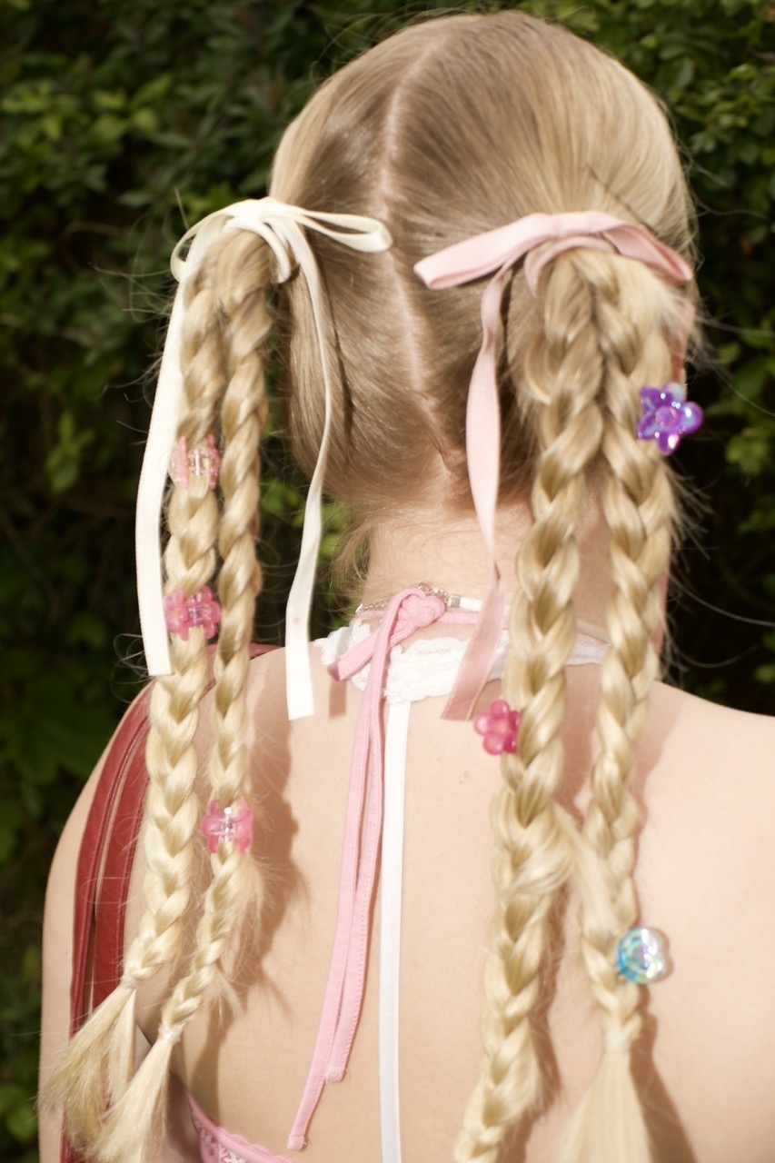 Model wearing plastic, colourful flowers in pleated hair.