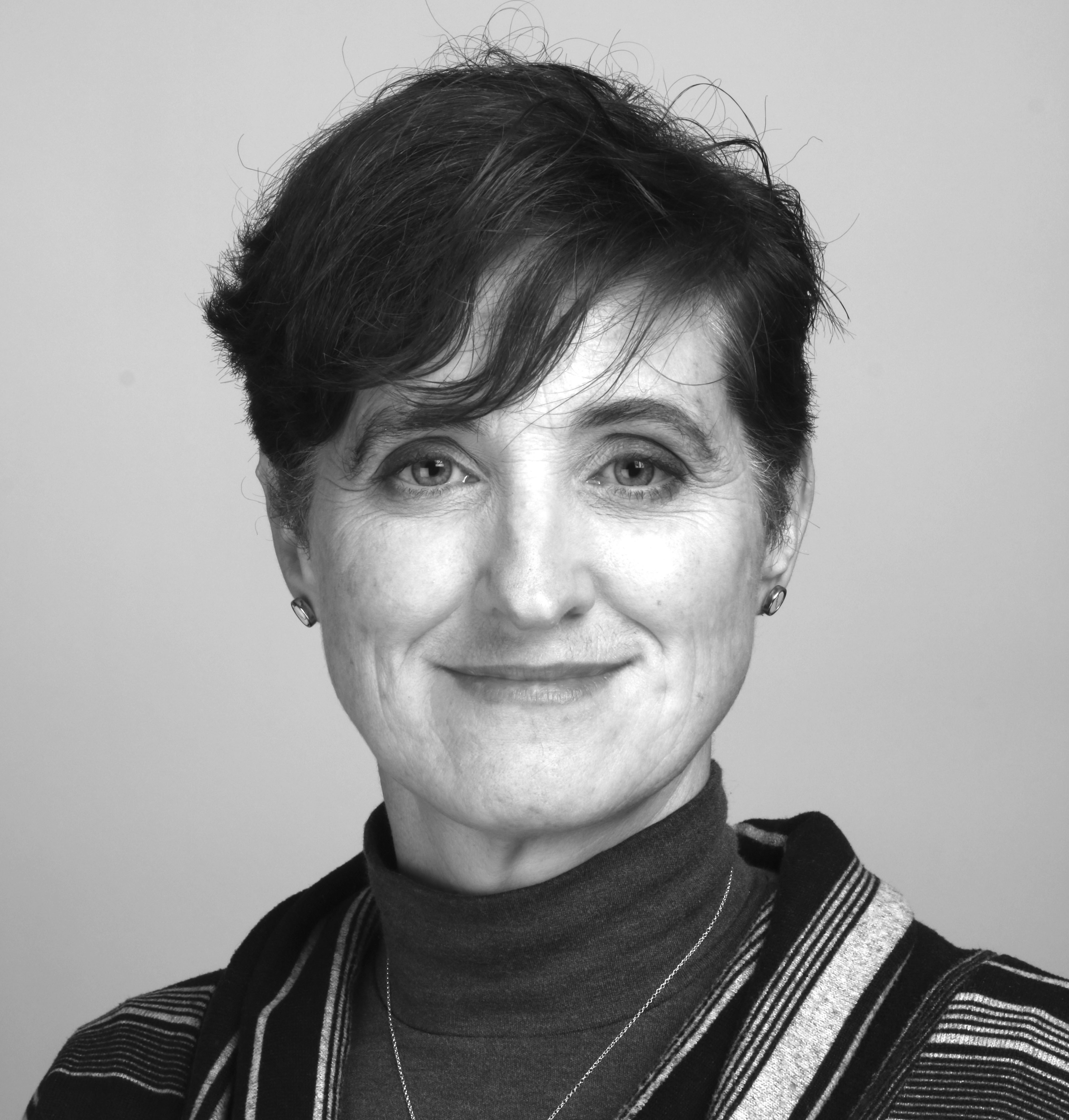 Black and white portrait of smiling woman with short dark hair wearing striped top against plain background.