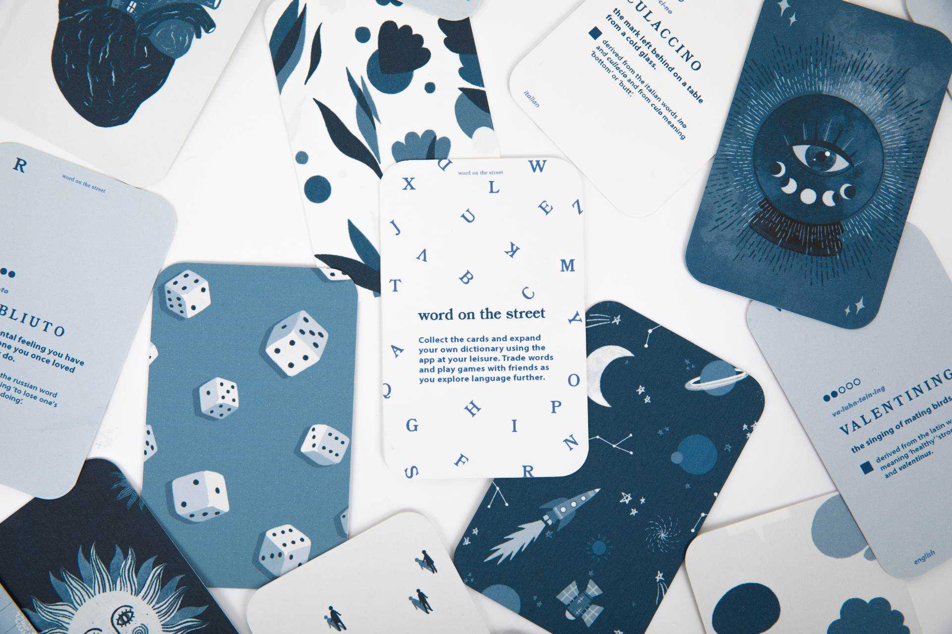 Cards with various designs on a plain surface. Card in the middle has different letters of the alphabet scattered around it and the text titled "word on the street" in the middle.