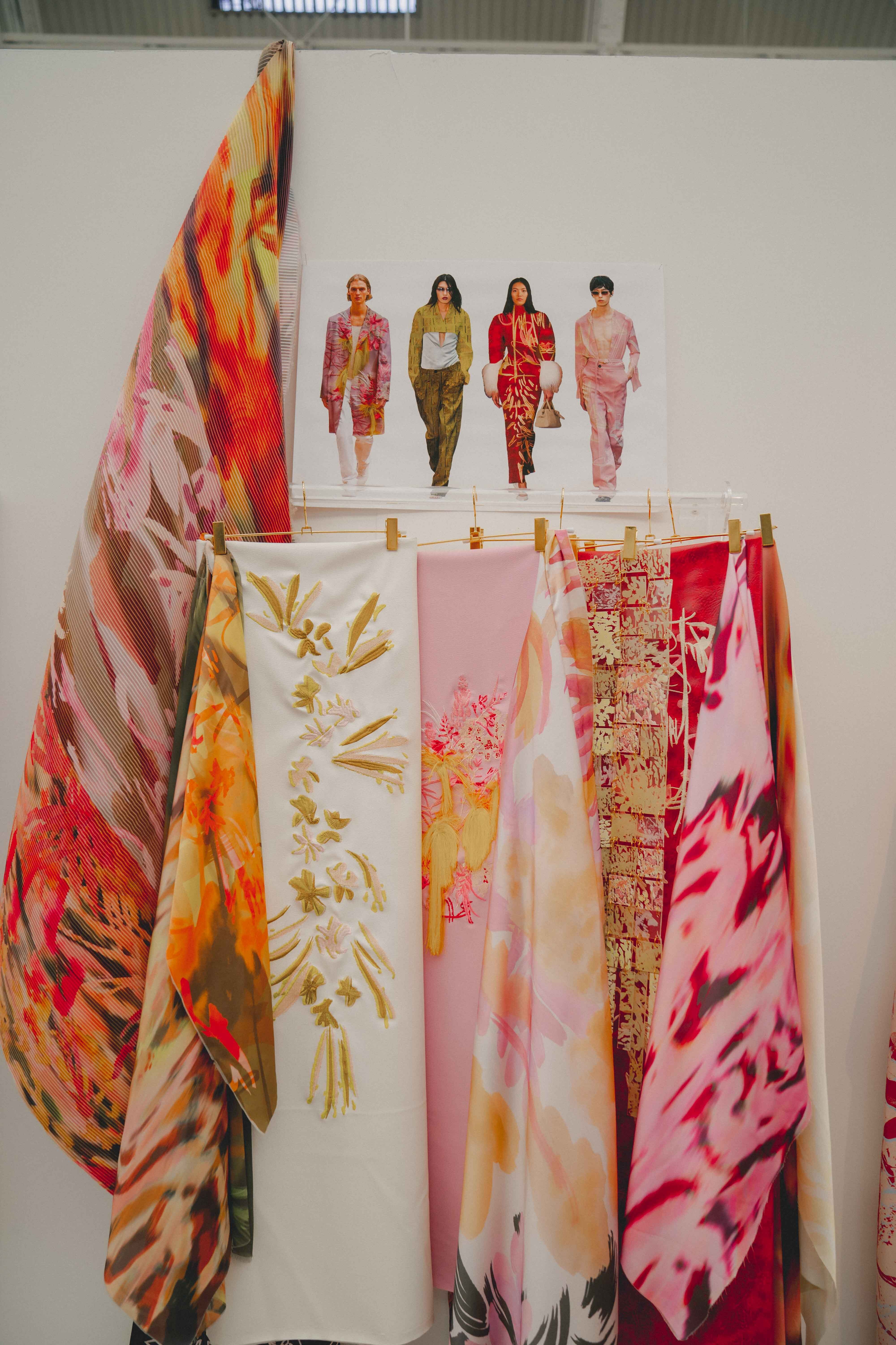 Illustration of four people walking down with colourful patterned scarves hung on clothesline in foreground featuring florals and geometric designs.
