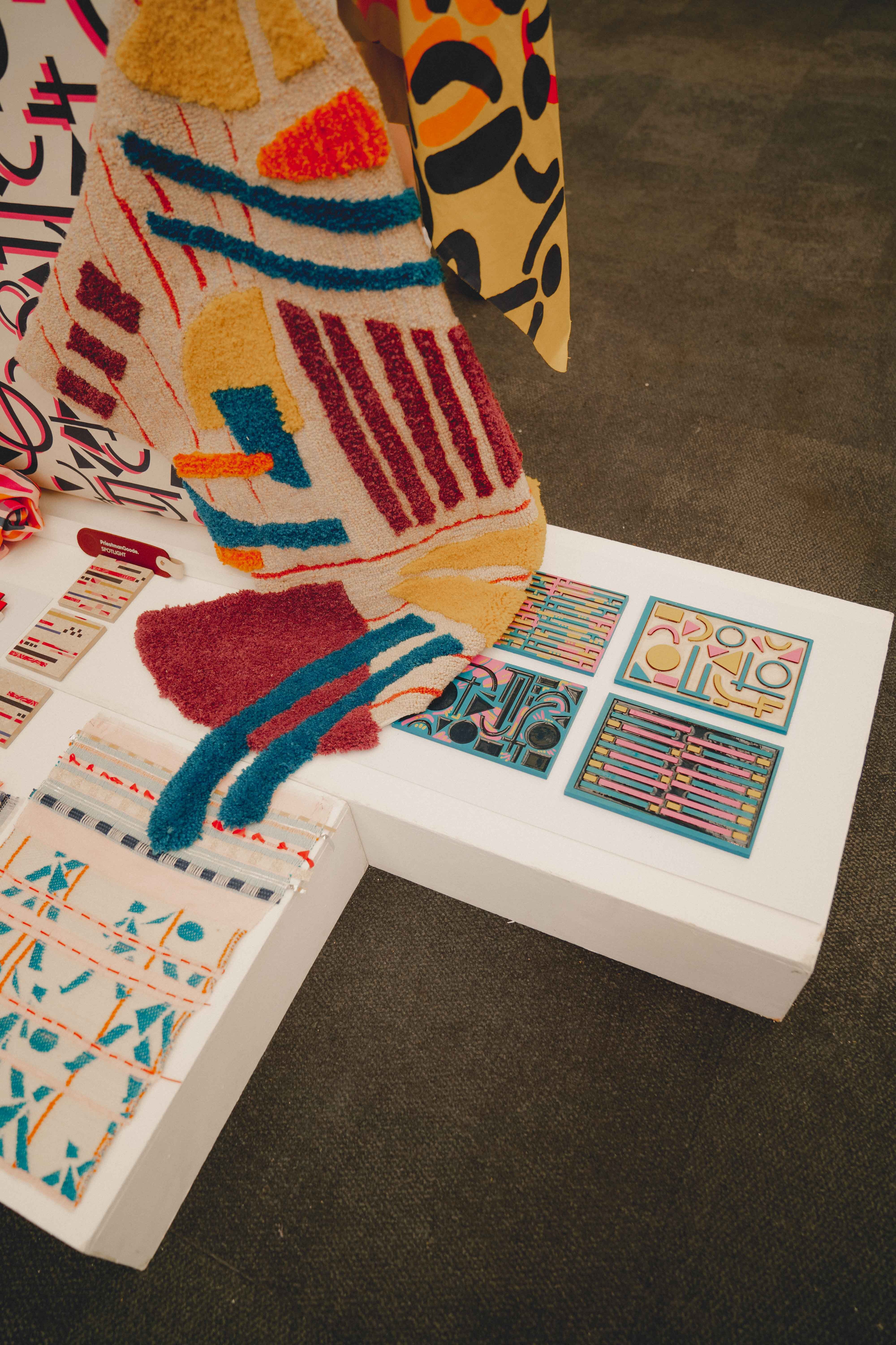 Colourful printed materials with geometric patterns, stripes, and abstract shapes in red, blue, orange, and yellow spread on dark surface.