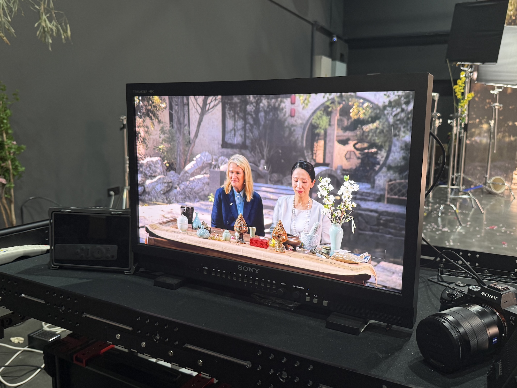 Monitor screen in a film production studio showing AUB Vice-Chancellor and CEO L Mann sitting at a tea table with a member of the leadership team at Nanjing University of the Arts.