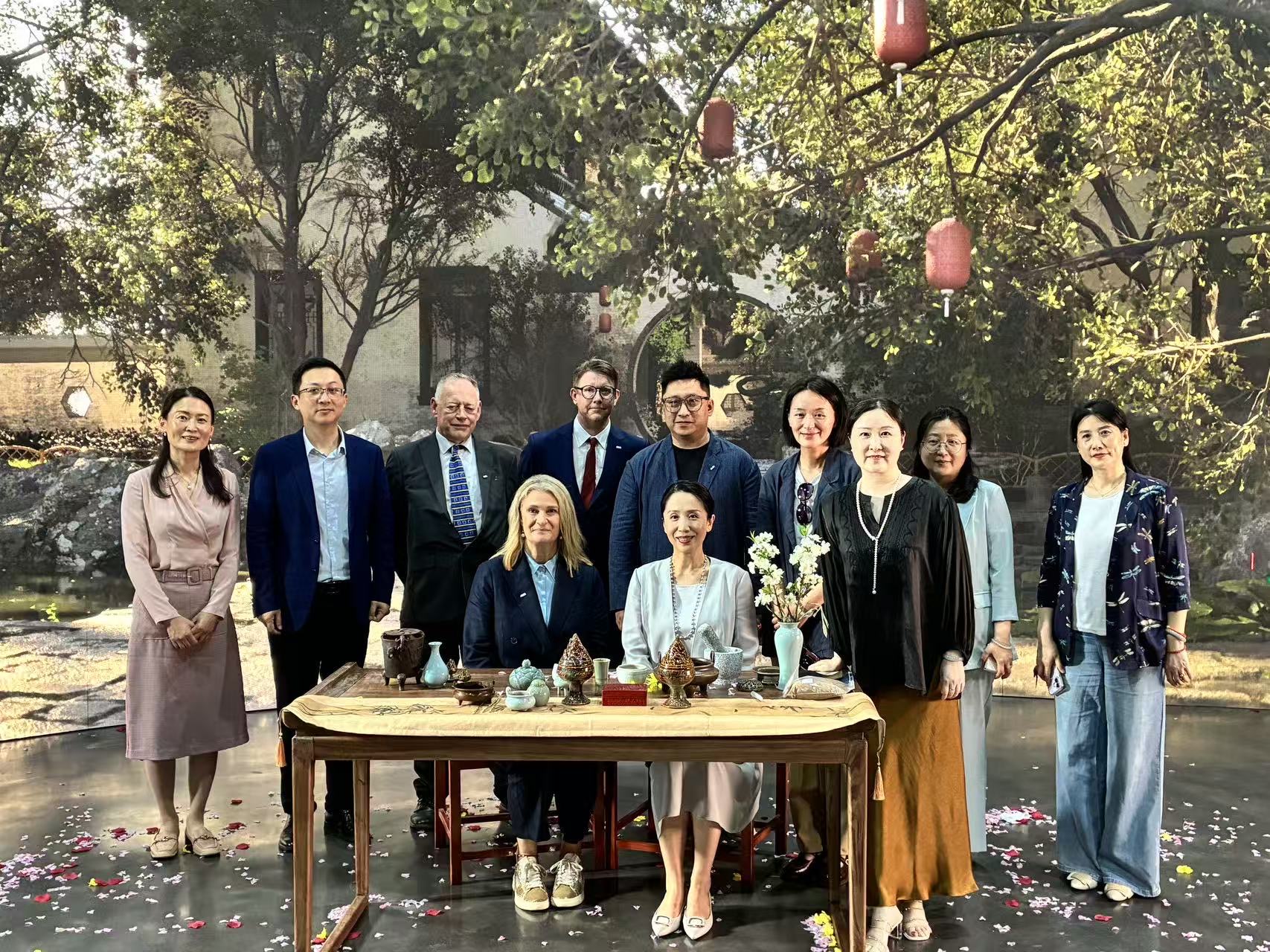 Group of staff from Arts University Bournemouth and Nanjing University of the Arts pose for a photo with trees and a house projected onto a green screen in the background.