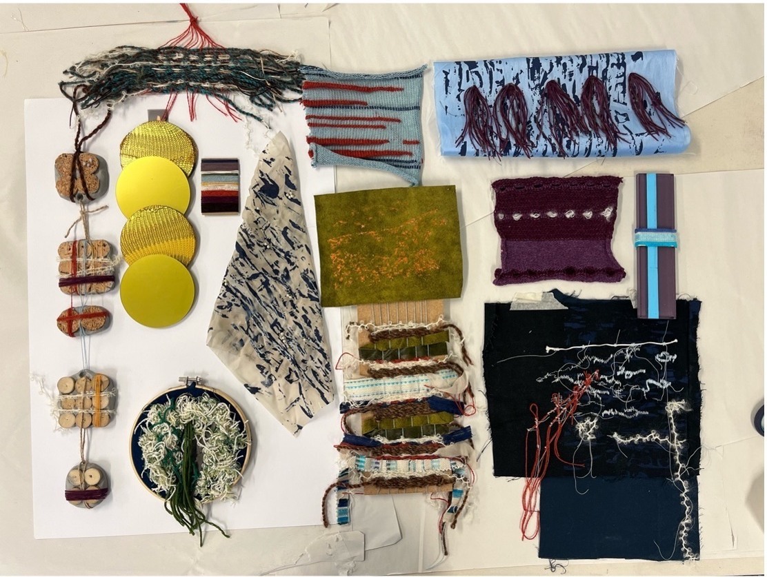 Collage of textiles and natural elements, gold, green and blue, on a plain background.