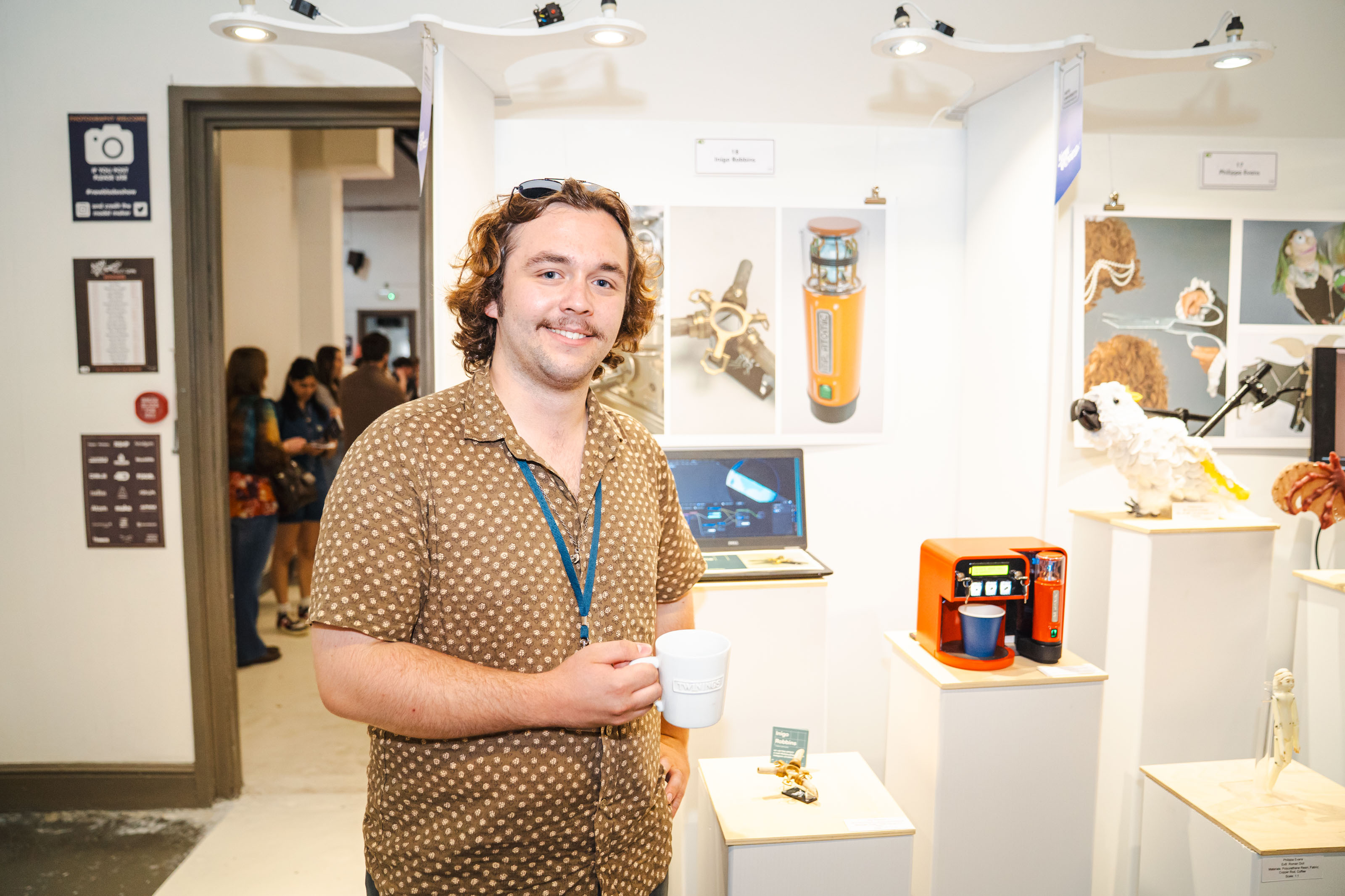 BA (Hons) Modelmaking graduate I. Robbins with stands in white room at New Blades Modelmaking Expo with display cases and artwork.