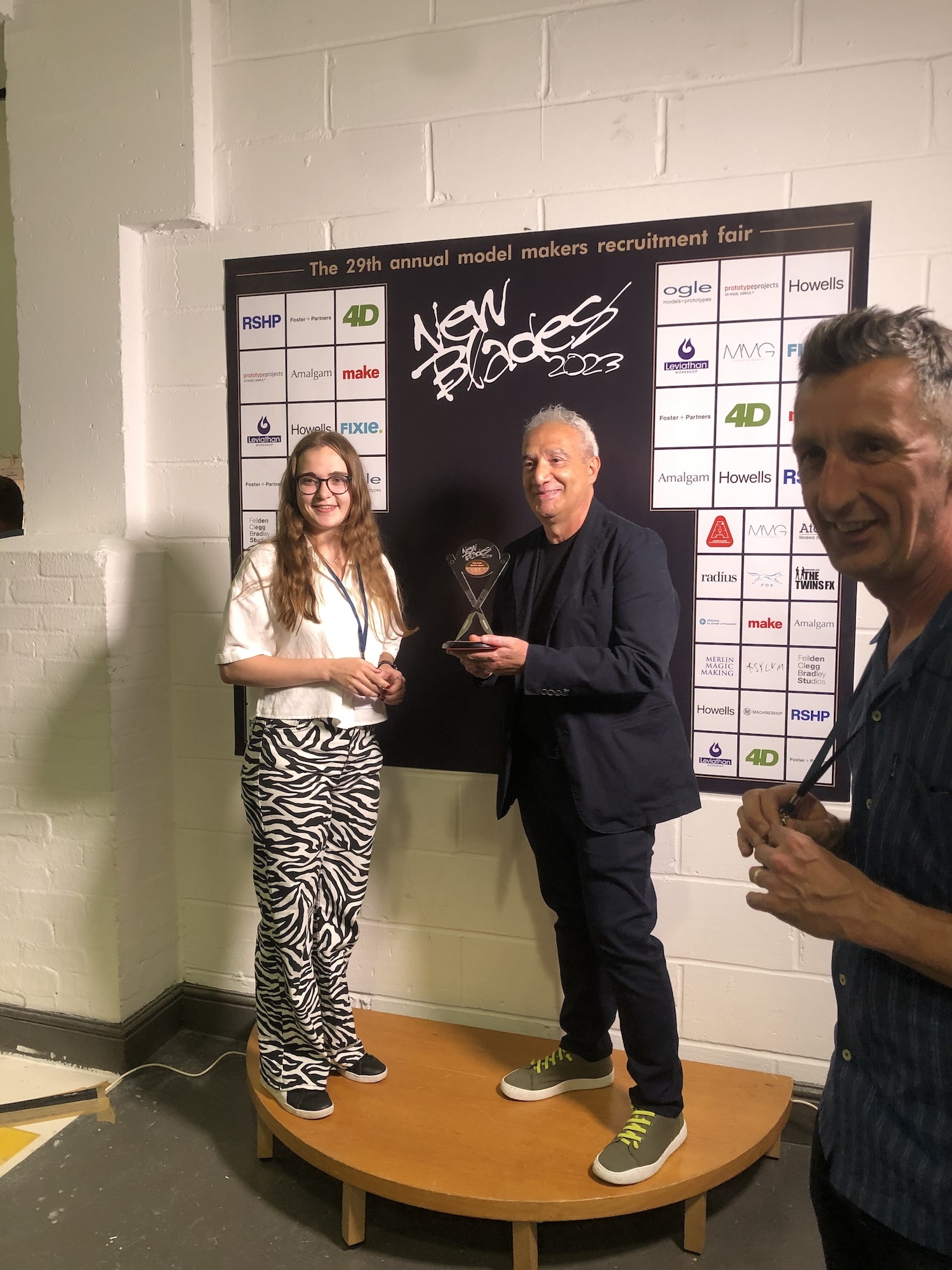 BA (Hons) Modelmaking student Holly Bignell standing on a stage with another person accepting an award.
