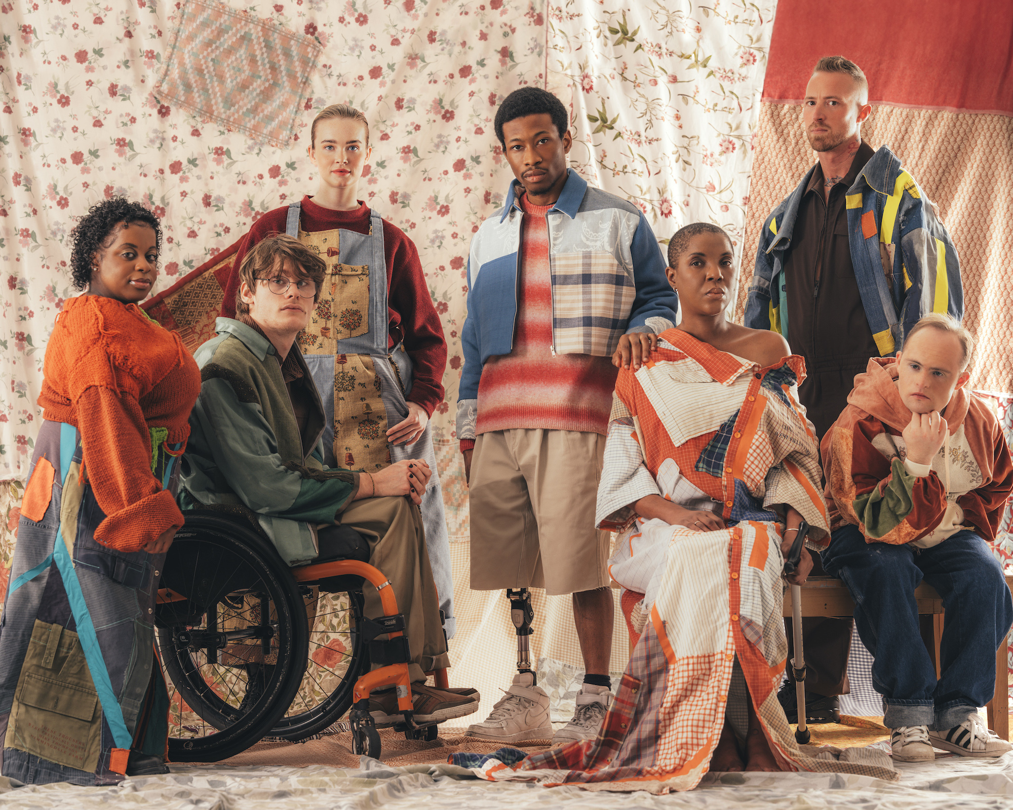 A group of people posing for a photo in front of a large tapestry.