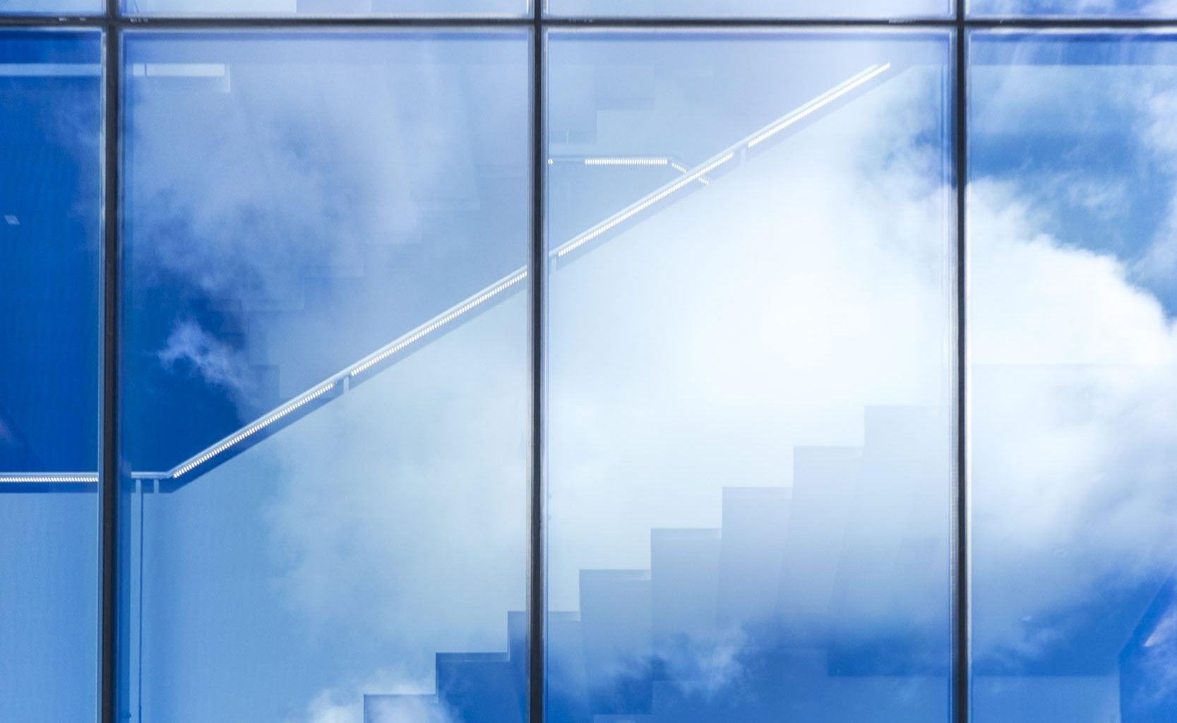 Outside view of stairs through a big glass window. Clouds are reflected off the window