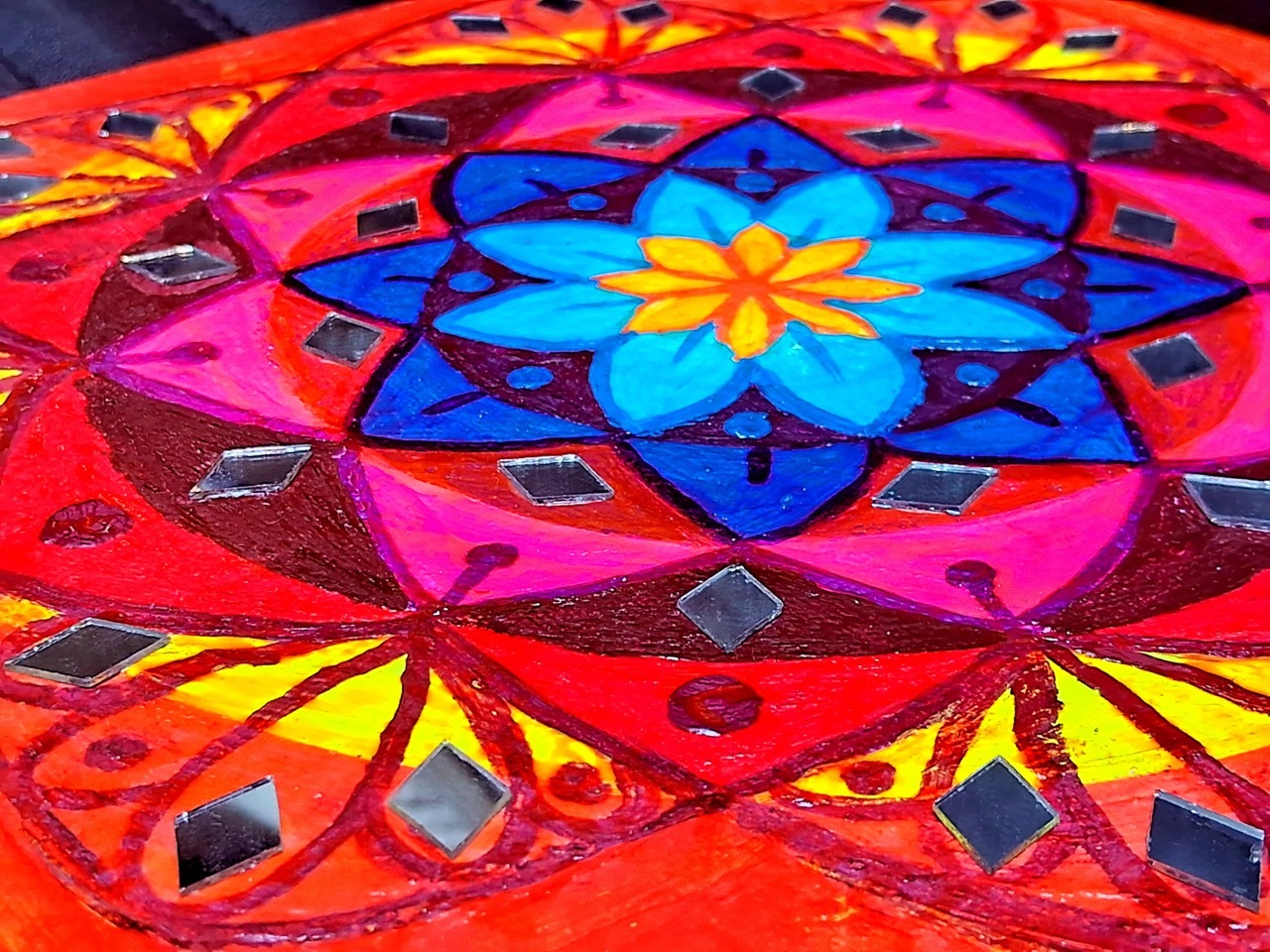 Colourful illustrated mandala with flowery motifs and pink, yellow, red and blue hues.