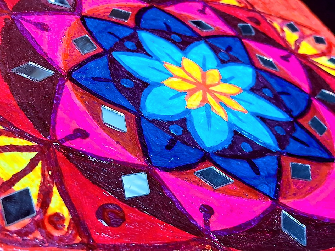 Colourful illustrated mandala with flowery motifs and pink, yellow, red and blue hues.