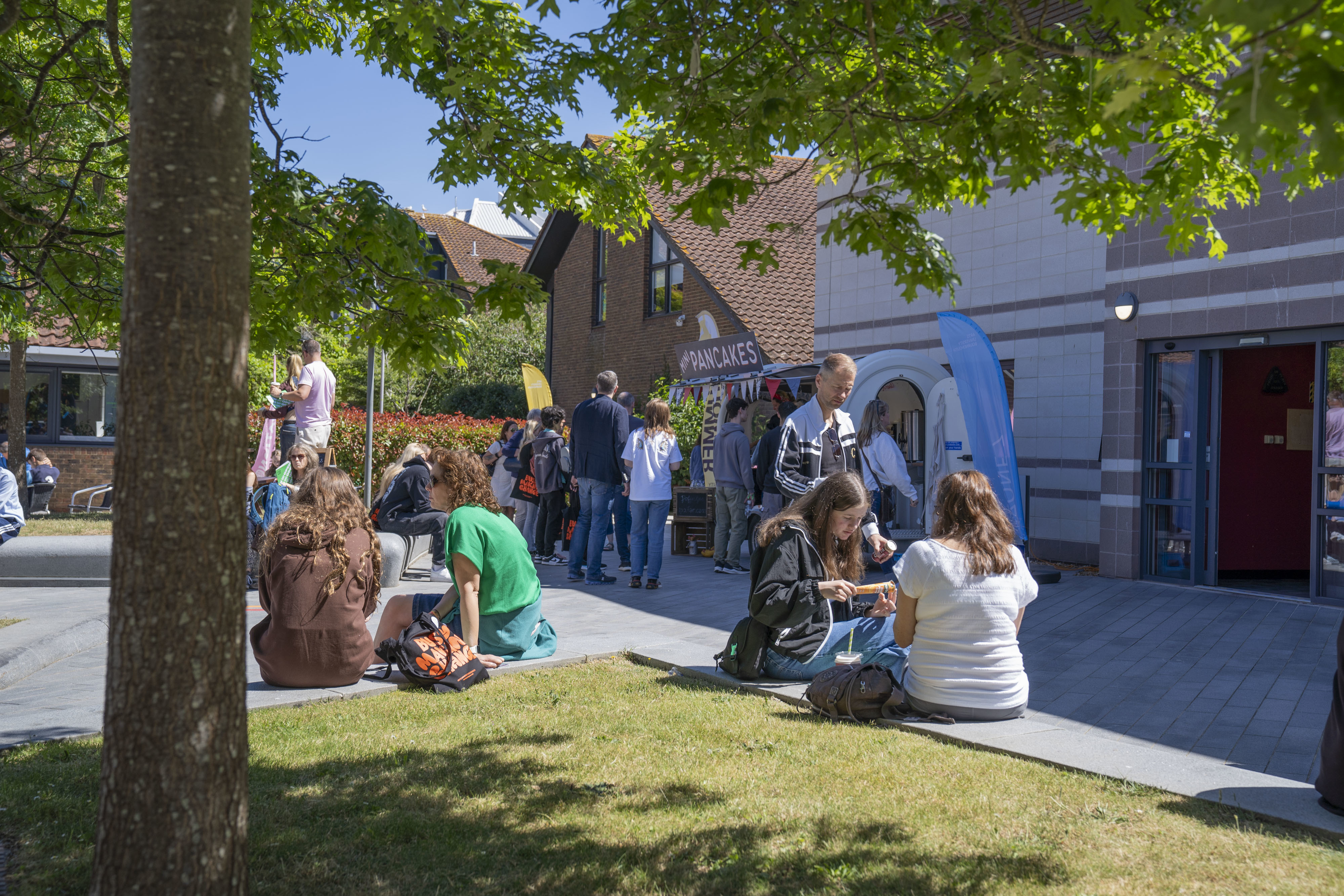 People sitting around AUB Campus outside the Library and pancake van on June 2024's Open Day.