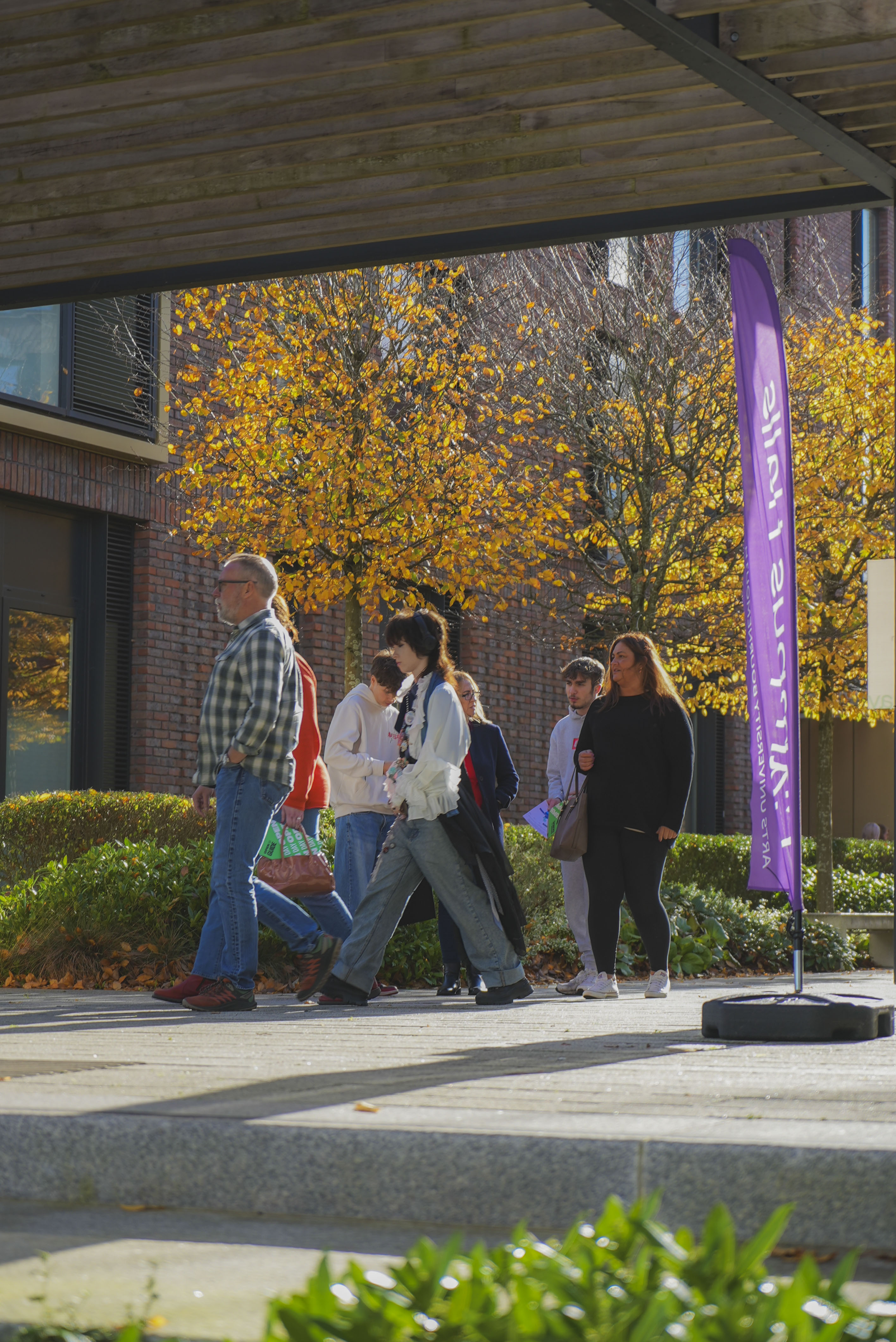 Students and parents in a group walking through AUB Campus Halls, purple flag, orange trees and brick building in the background.