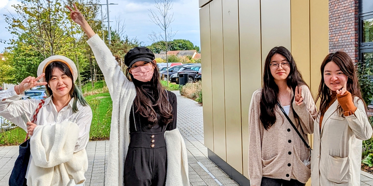 Four International AUB students pose for a photo outside the on-site halls of residence.