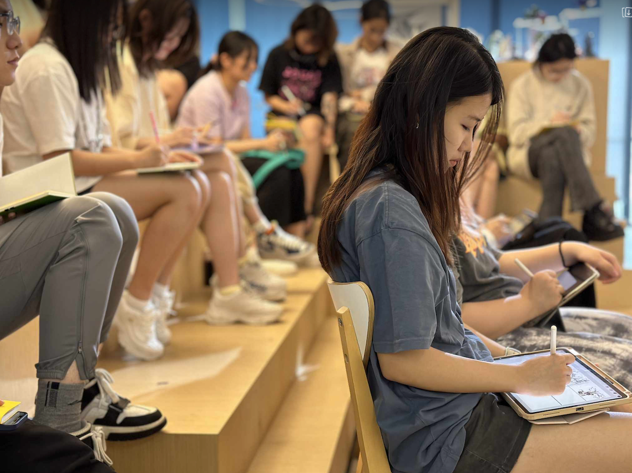Students sitting in a lecture theatre writing in notepads and on tablets.