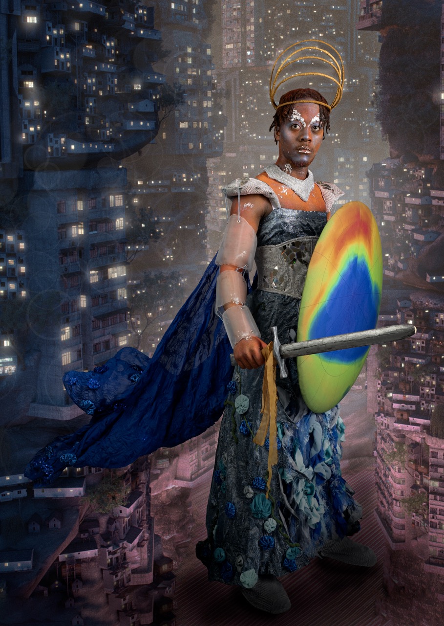 A woman in ornate costume with a glowing halo-like headpiece holds a rainbow-coloured shield and sword, standing against a backdrop of dense high-rise buildings.