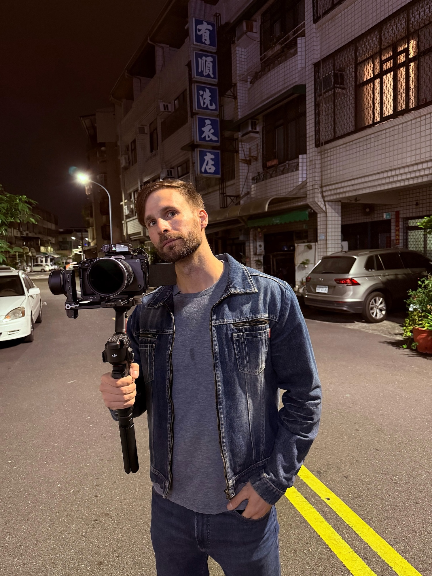 Actor and filmmaker P Kertesz holding a camera on a tripod standing in a Taiwanese street.