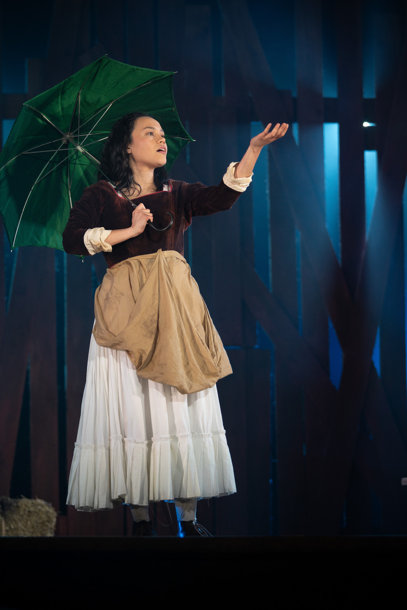 AUB Productions' 'The Ballad of Maria Marten' – actor in period costume with a green umbrella, wood panel background.