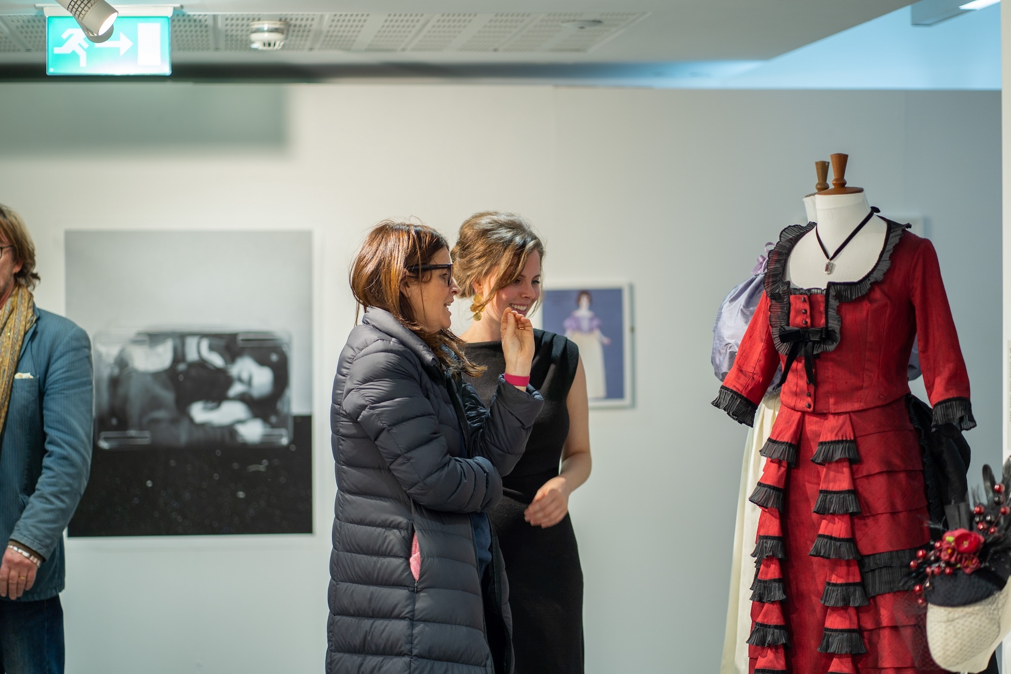 Two people looking at a red and black dress on a mannequin at the 2024 AUB Postgraduate Winter Show.