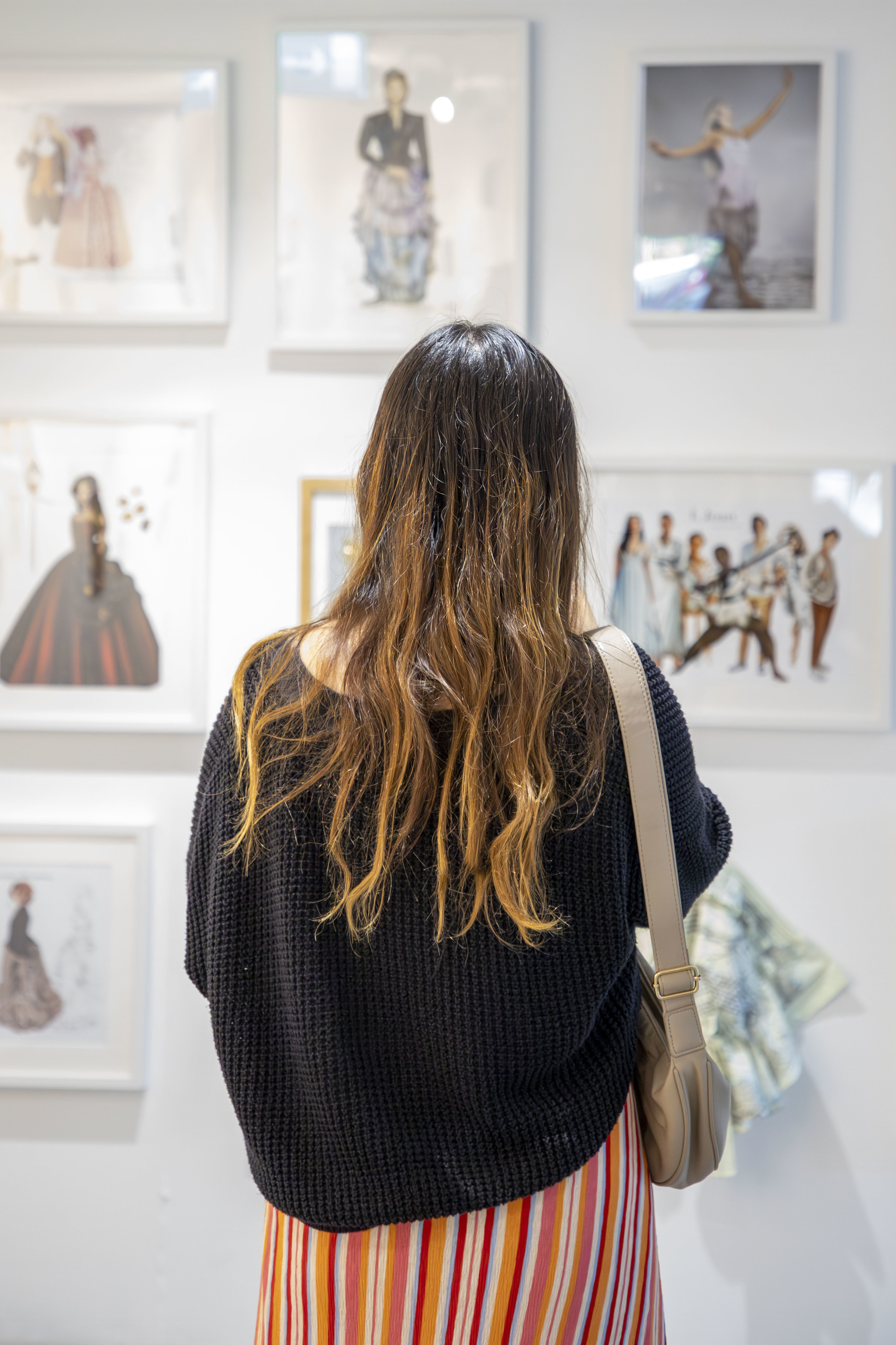 A person attending the September 2024 Postgraduate Summer Shows formal opening at AUB, viewed from the back while looking at artworks of display.