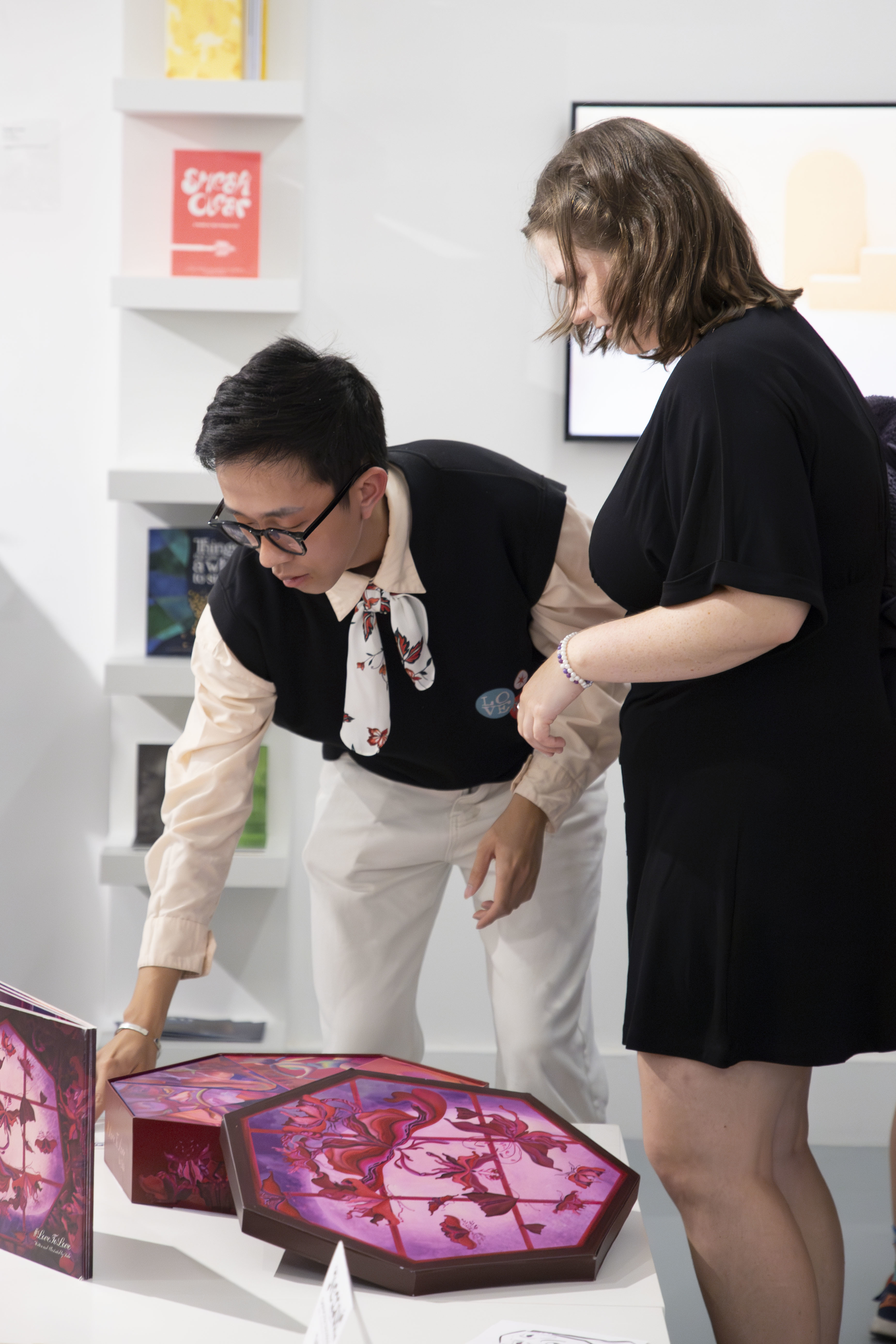 MA Illustration student M H Nguyen showing their work to an attendee of the Postgraduate Summer Shows on AUB Campus.